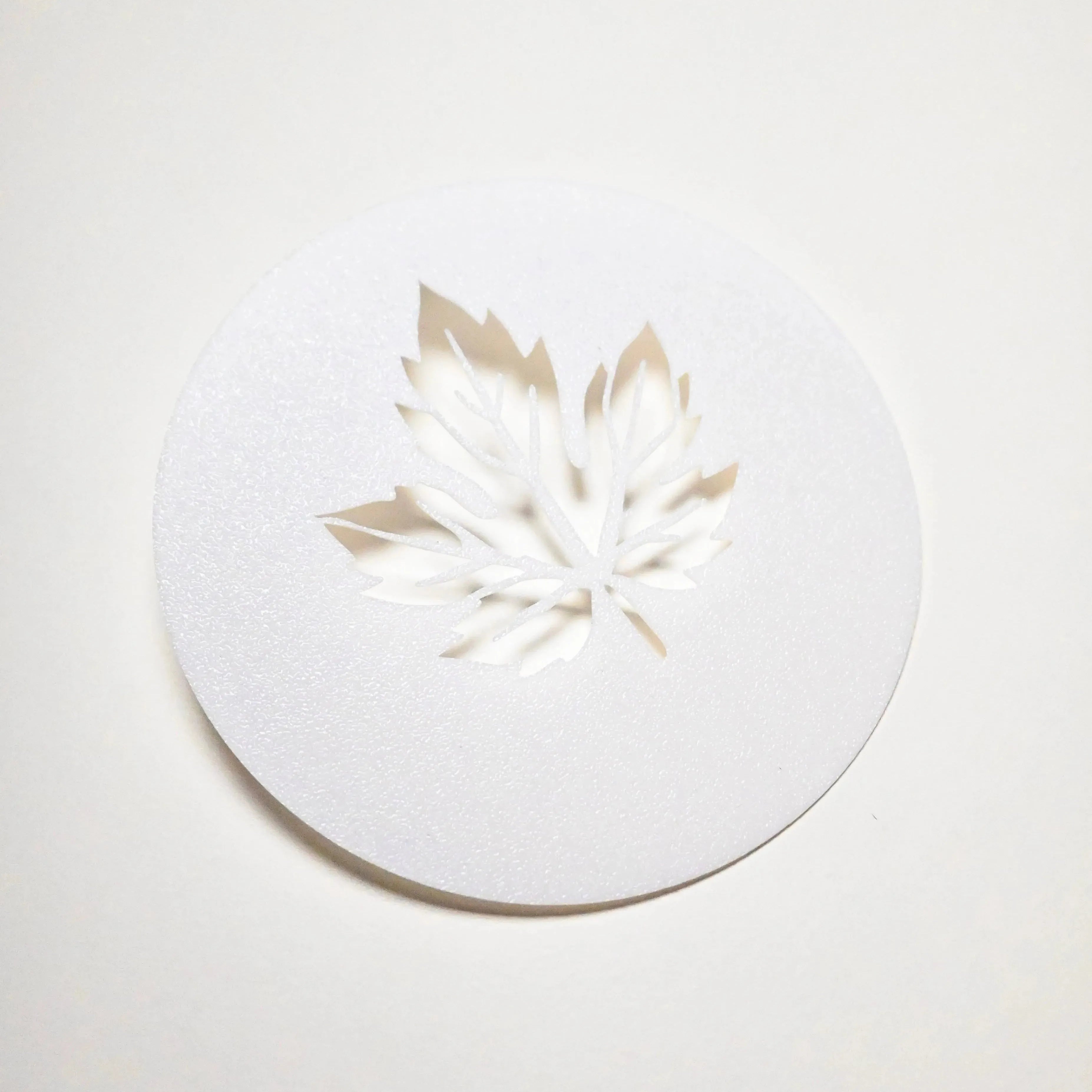 White circular plastic pastry stencil with a detailed vine leaf cutout.