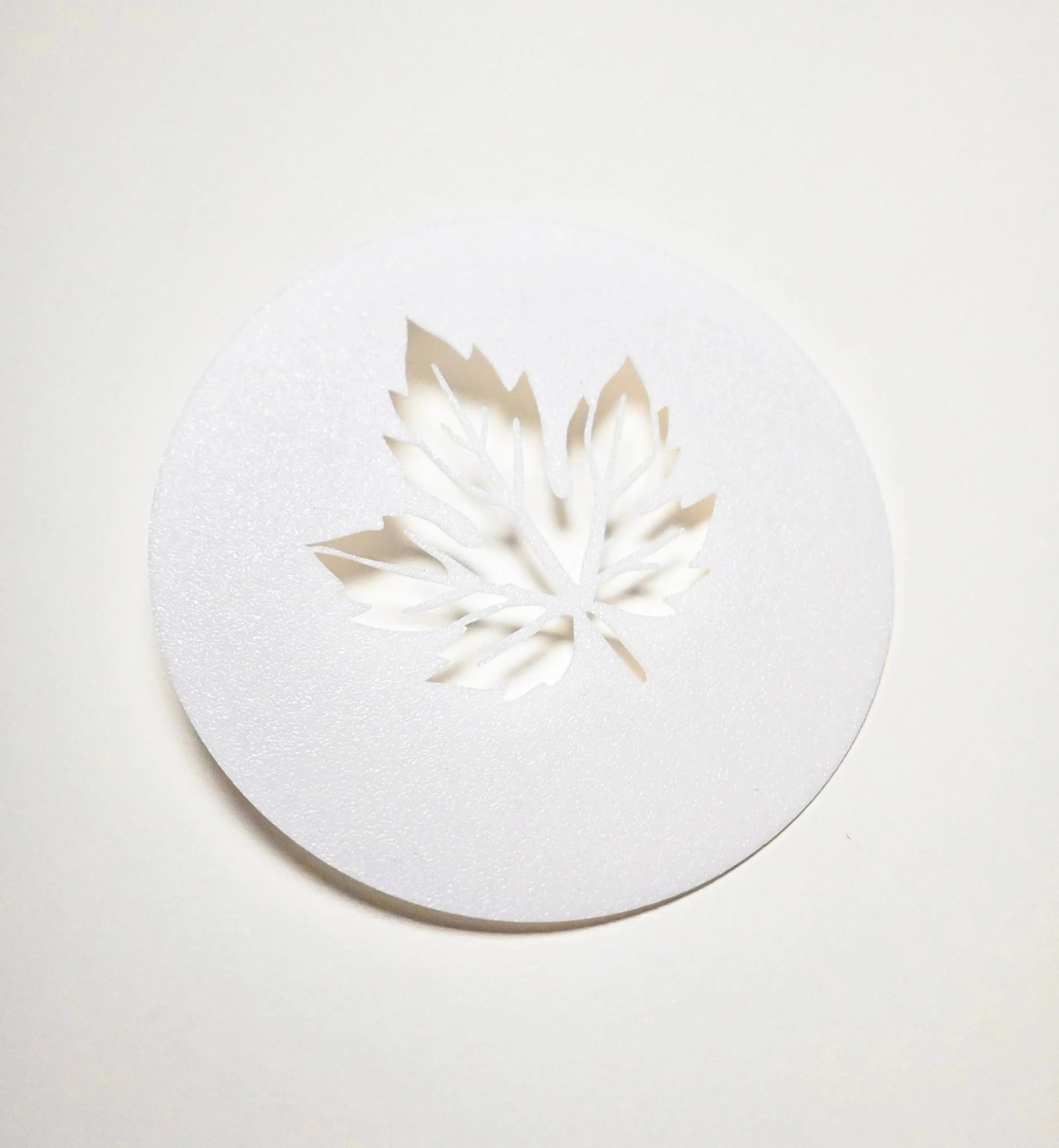 White circular plastic pastry stencil with a detailed vine leaf cutout.