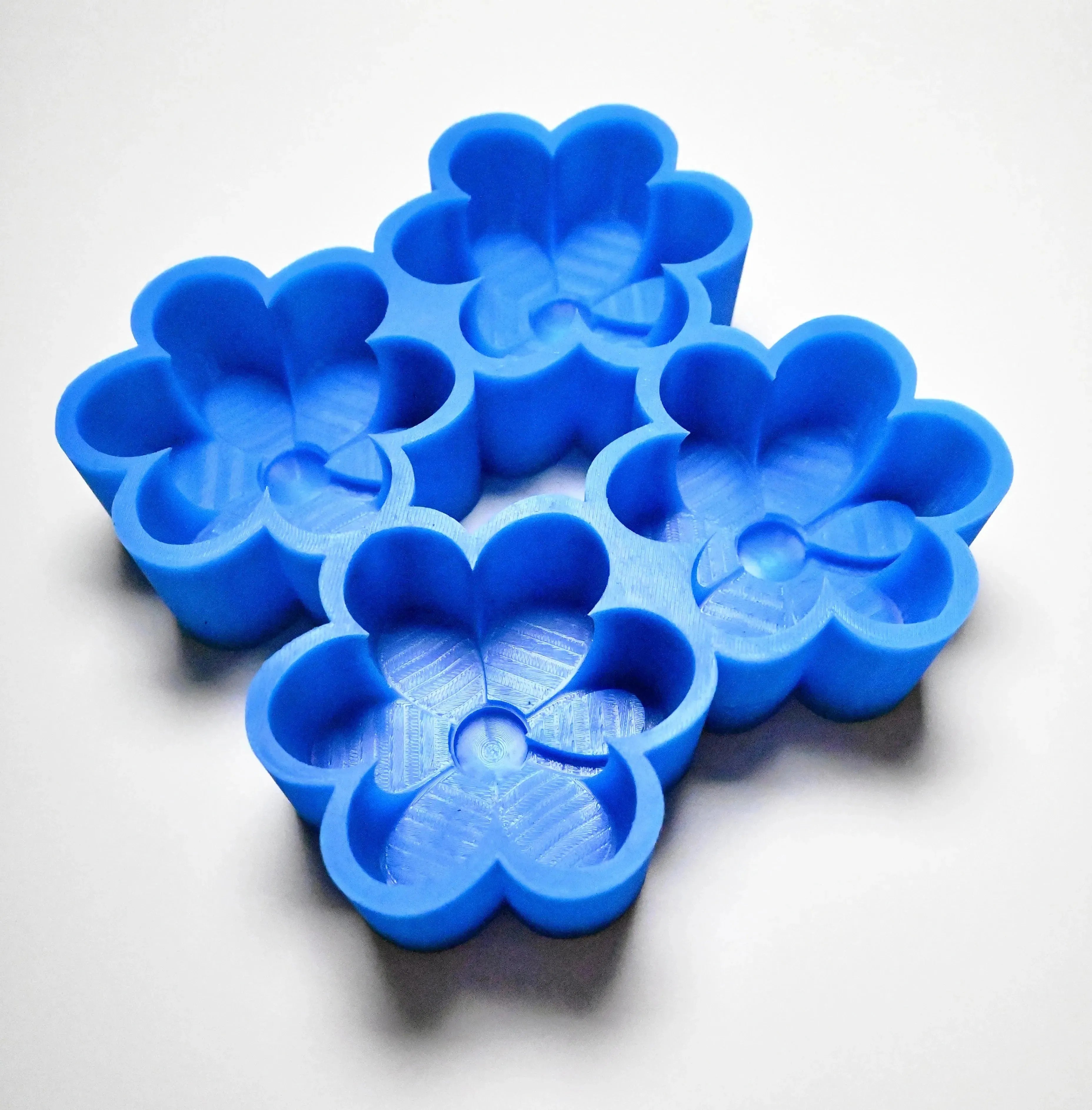 Blue silicone daisy mold with four detailed flower-shaped cavities.