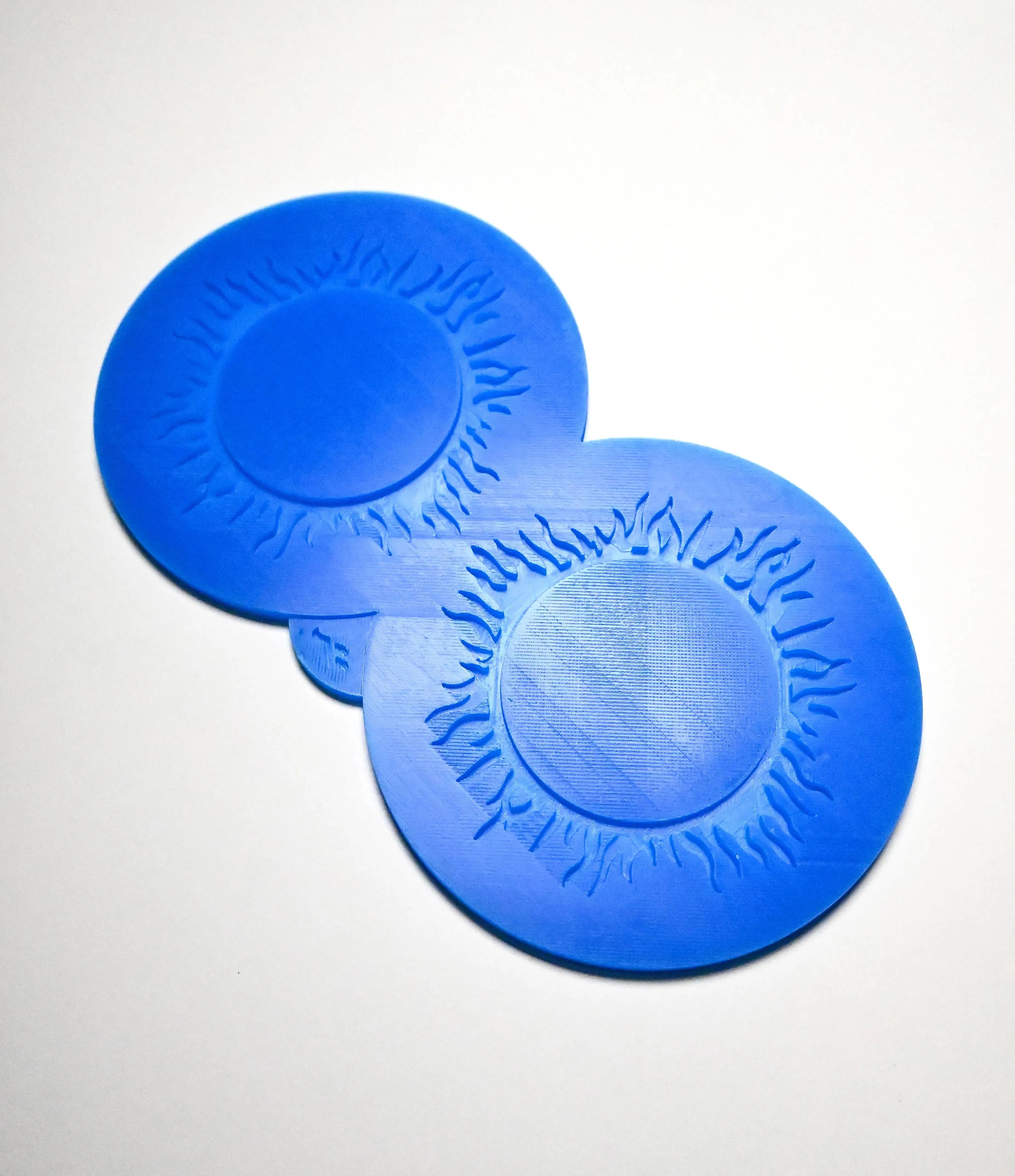 Blue silicone Spirulina tuile mat with two circular, sunburst-patterned molds.