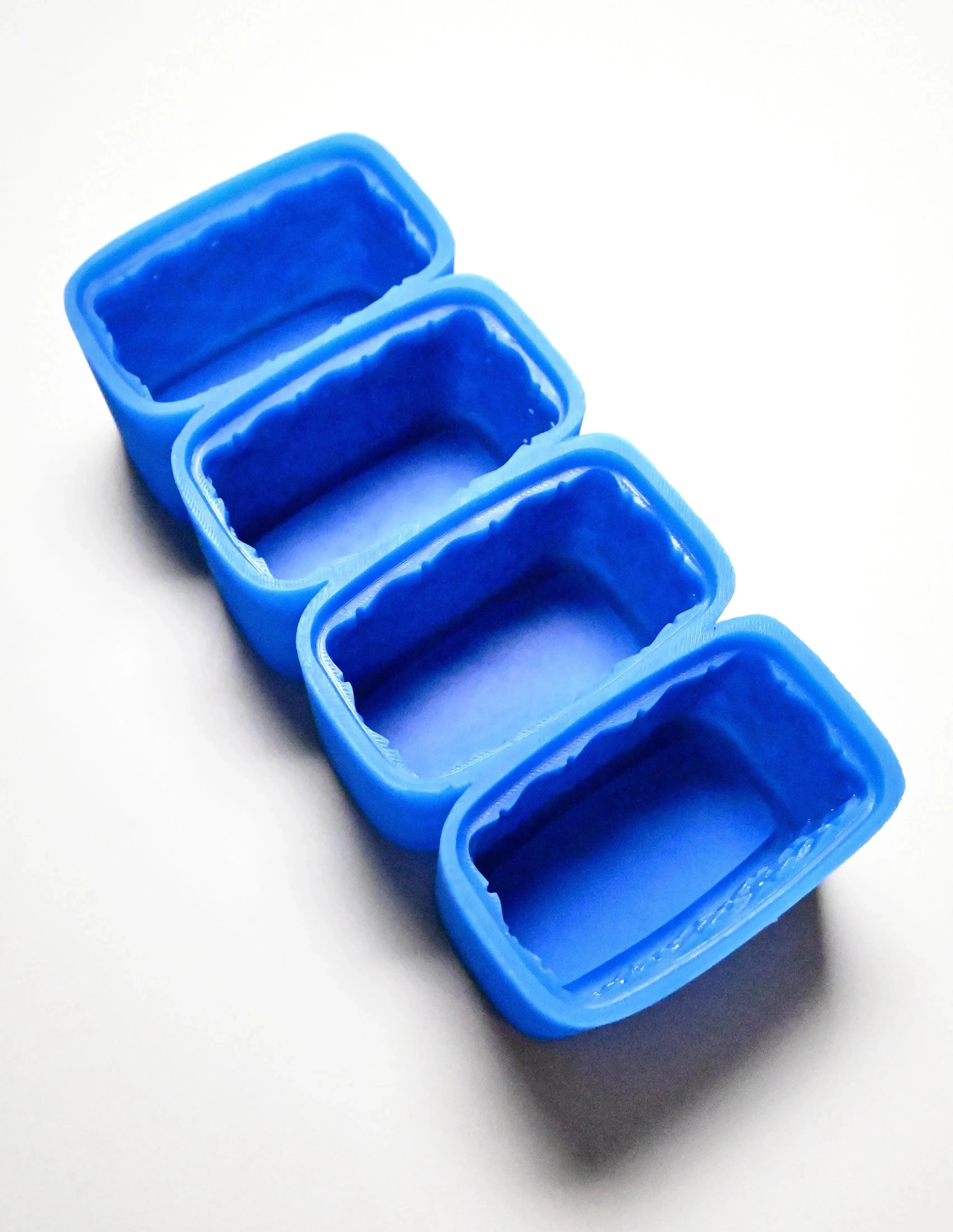 Four rectangular blue silicone basket molds lined up on a white surface.