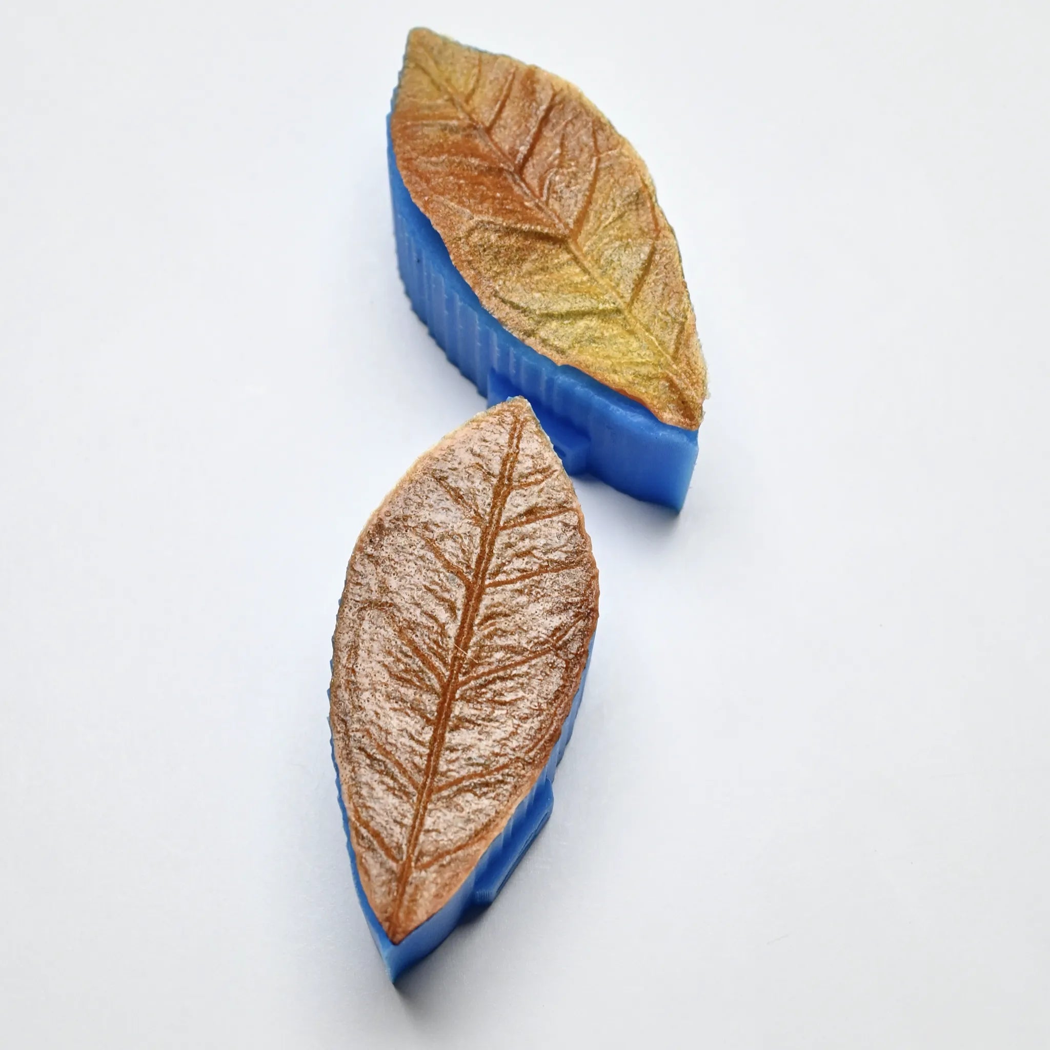 Two blue silicone tea leaf presses showing detailed leaf-shaped molds with realistic vein textures.