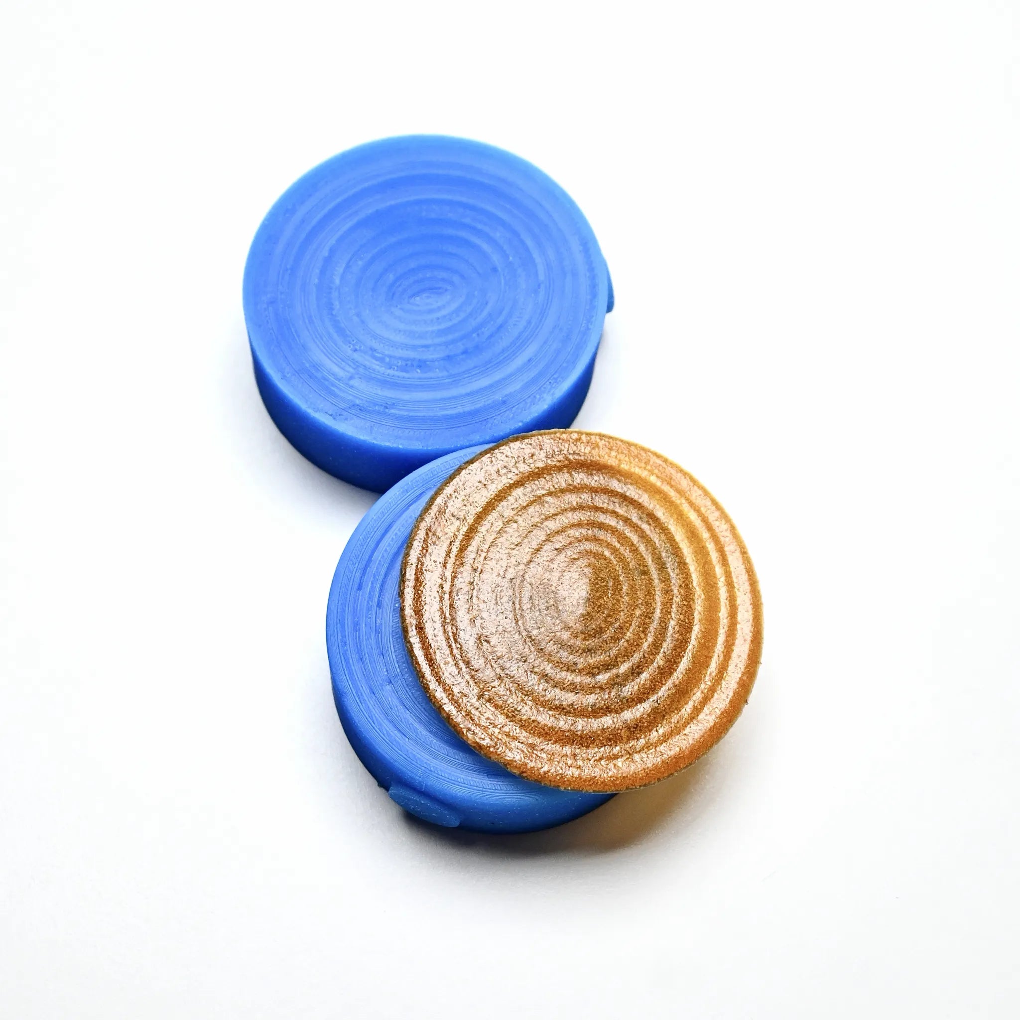 Blue round silicone Resonance pastry press molds with a textured spiral gold disk.
