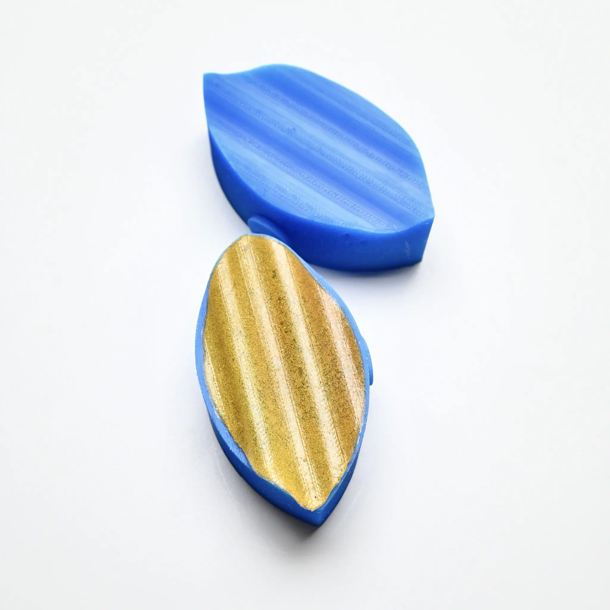 Blue silicone wavy calisson pastry press with a textured gold leaf-shaped mold.