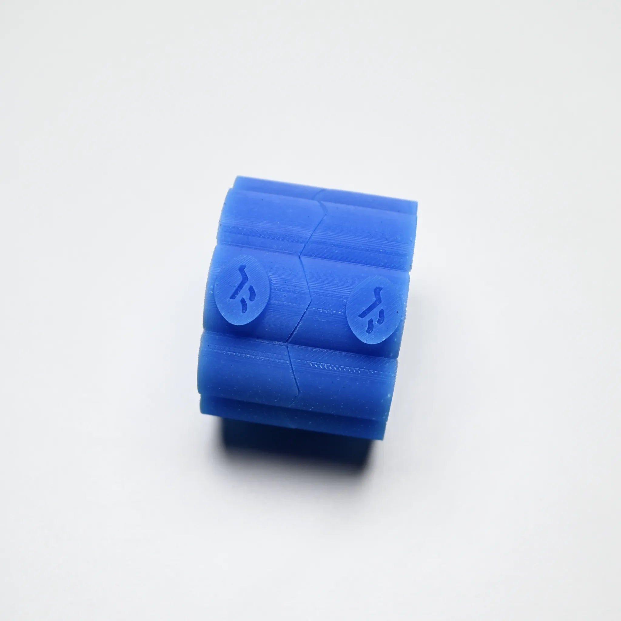 Blue silicone Helios pastry press with a cylindrical shape and textured chevron patterns.