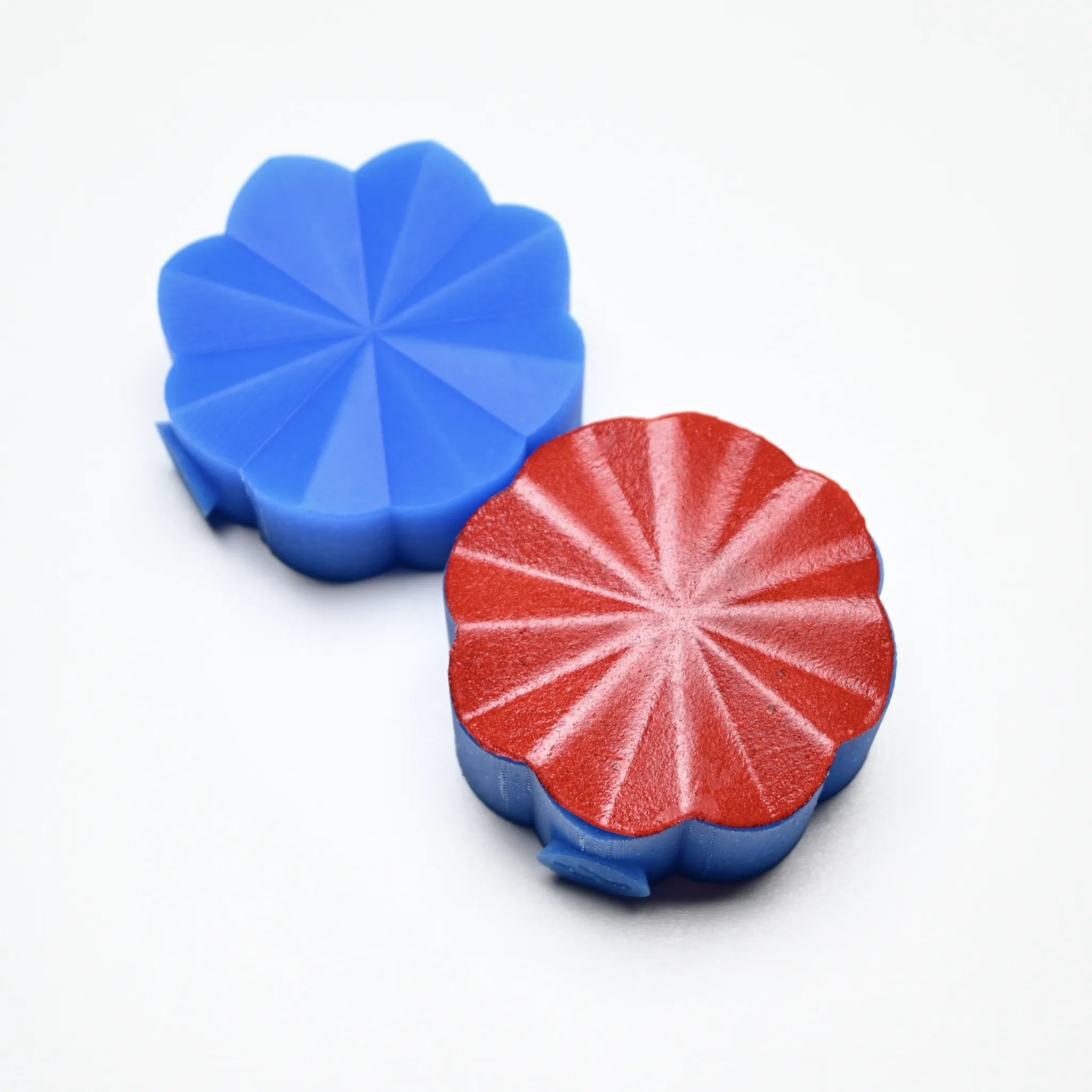 Blue and red Helios silicone pastry presses with a scalloped, radiant sunburst design.