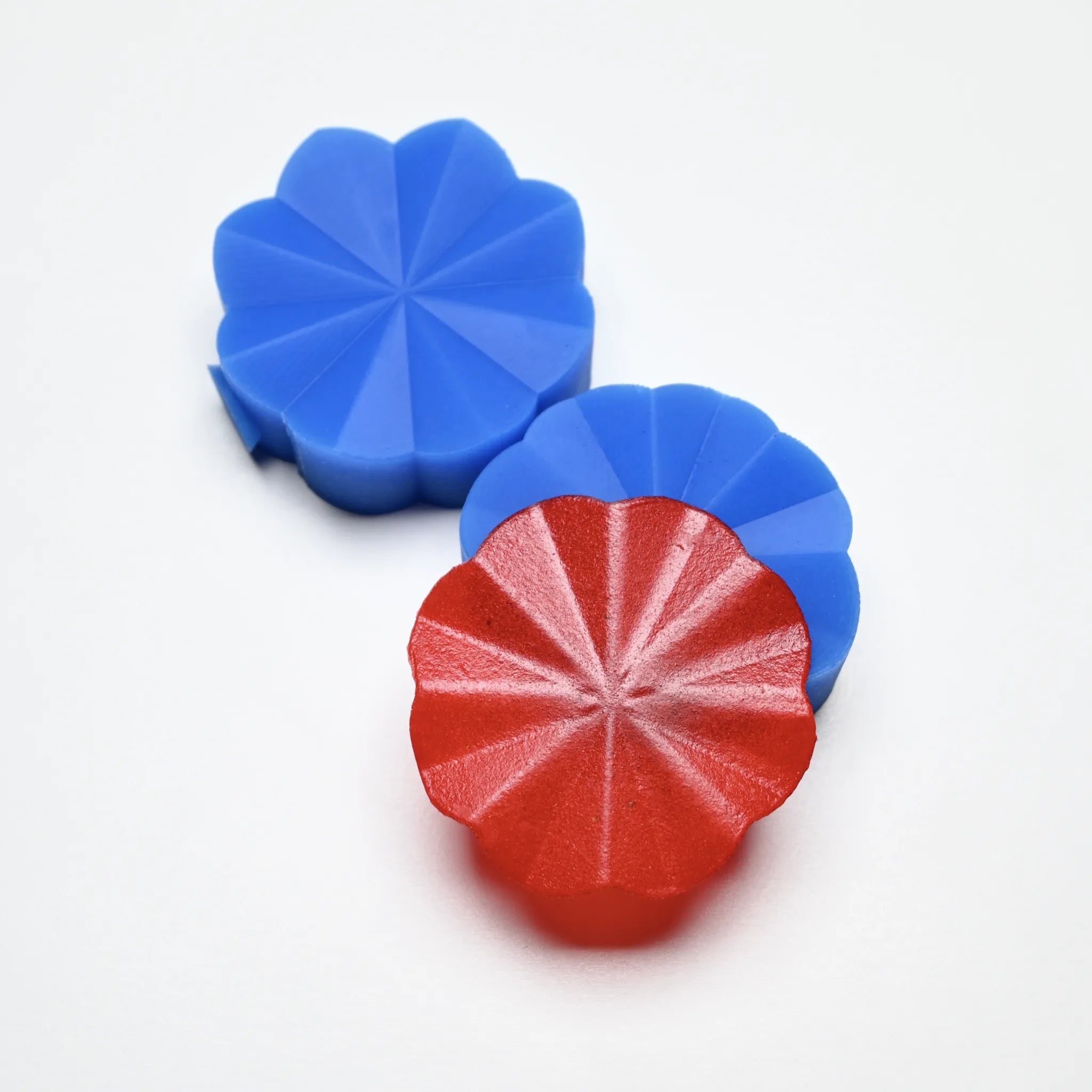 Two blue silicone Helios pastry presses with a red flower-shaped molded decoration.