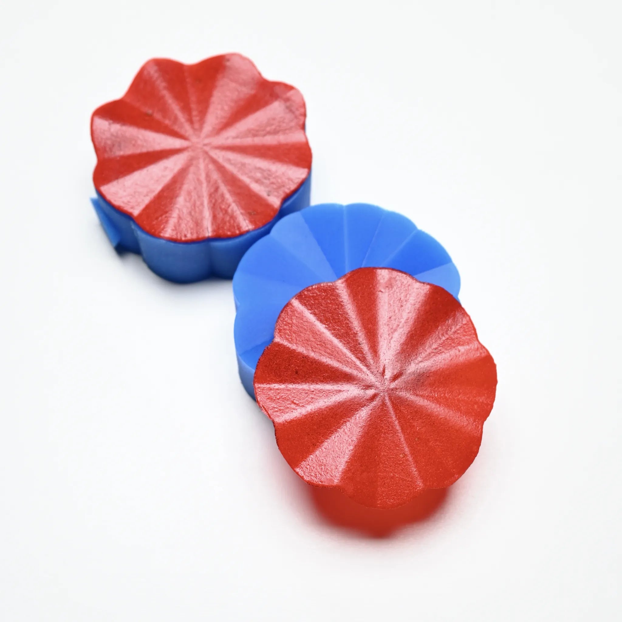 Helios blue silicone pastry press with scalloped, starburst-patterned red molds.