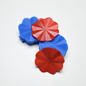 Blue silicone Helios pastry presses with flower-shaped, pleated red decorative elements.