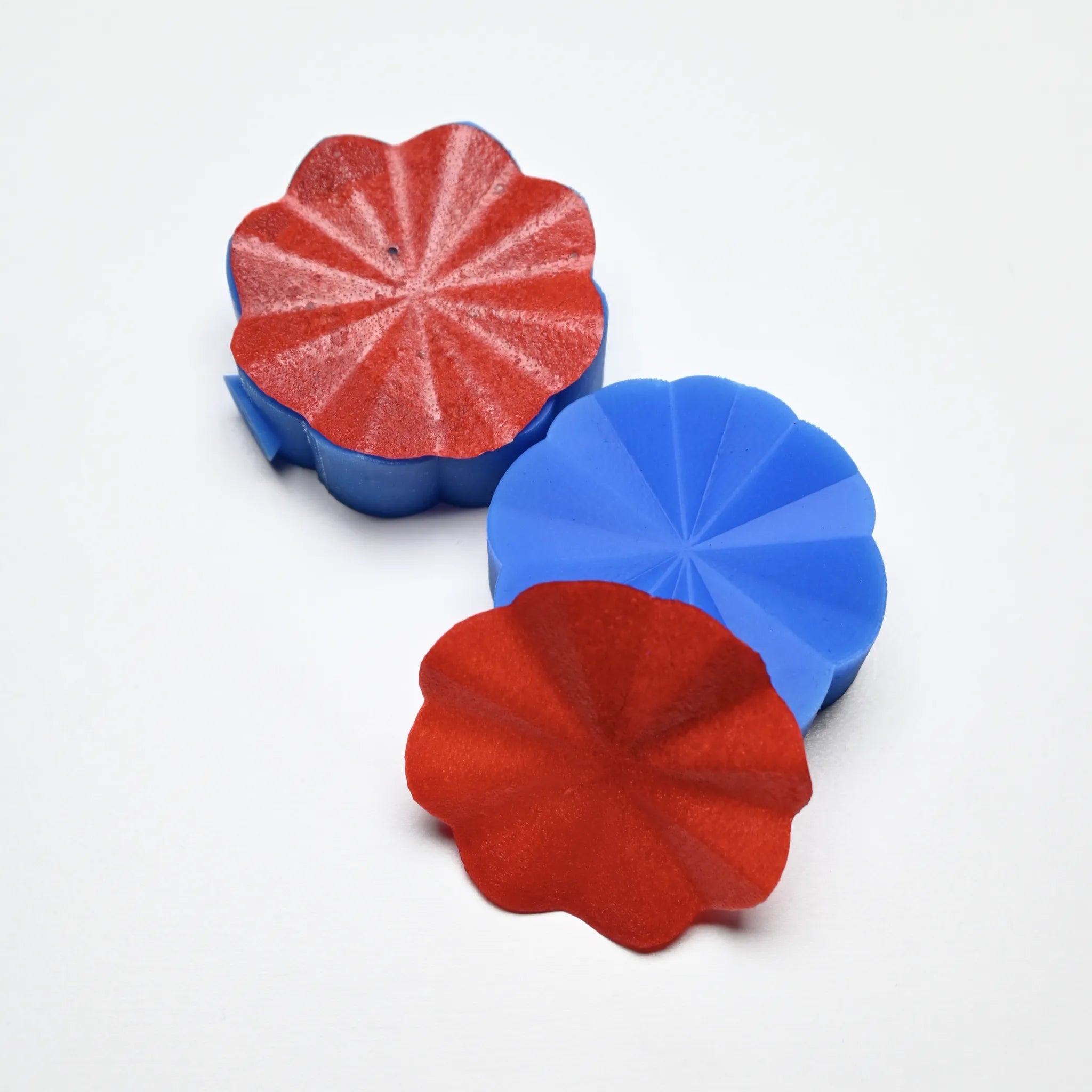 Blue silicone Helios pastry press molds with wavy, flower-like ridges and red textured tuiles.