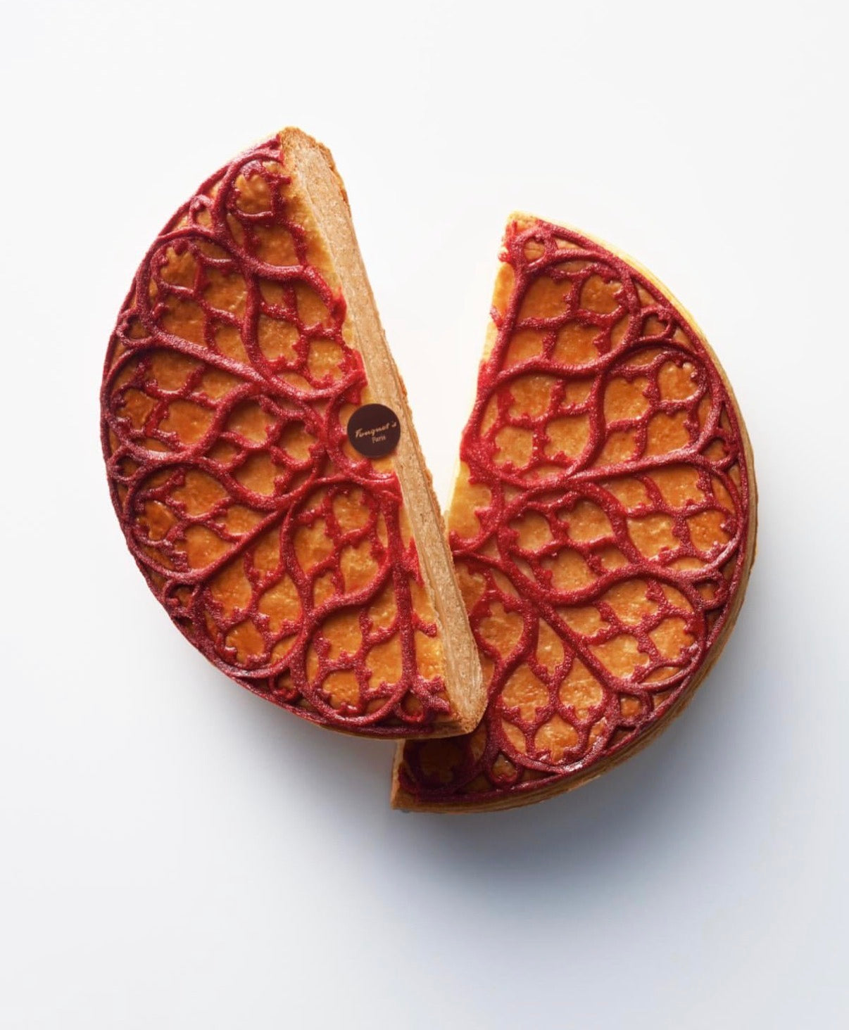Red ornamental lace tuile on a sliced golden pastry, made with the Regalia silicone mat.