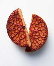 Red ornamental lace tuile on a sliced golden pastry, made with the Regalia silicone mat.