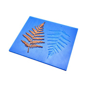 Blue silicone mat with detailed fern leaf molds and a bronze-colored tuile.