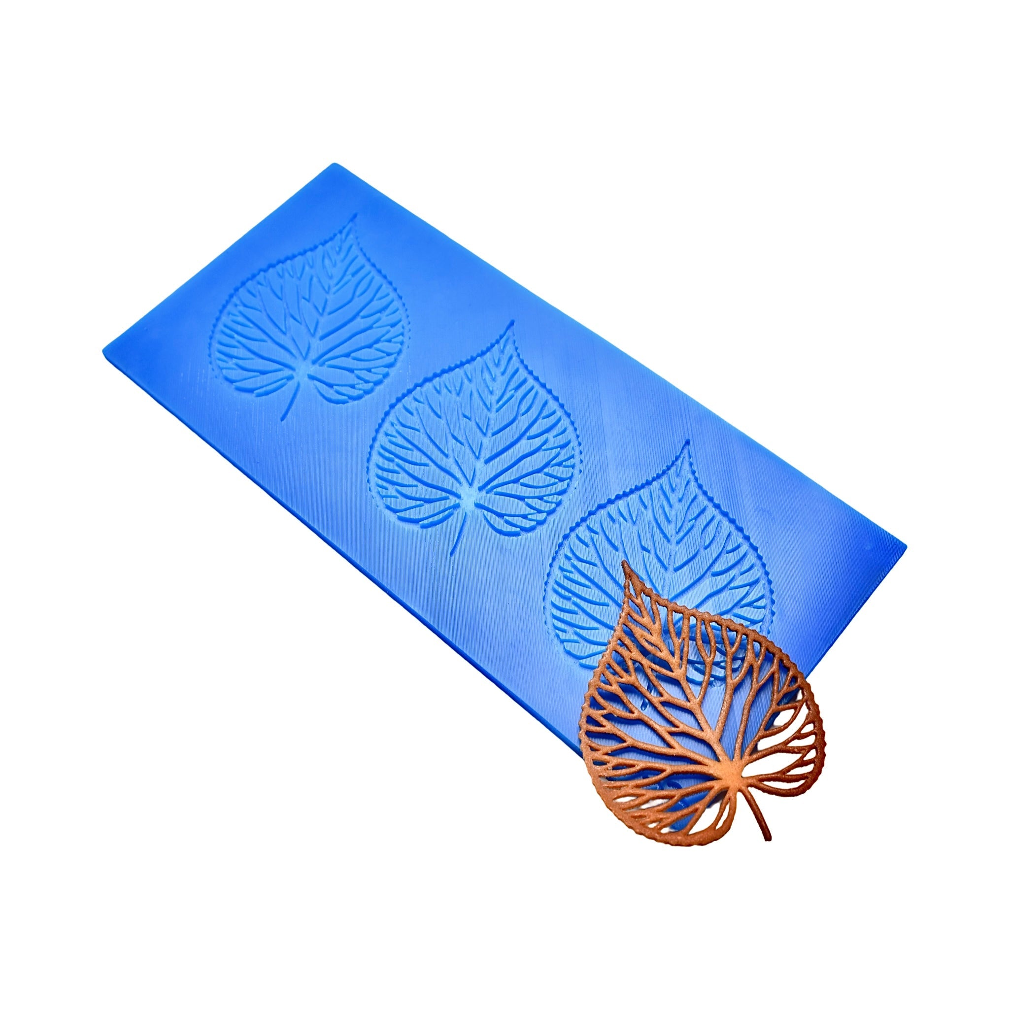 Blue silicone Tilia tuile mat with three leaf-shaped molds and a finished bronze linden leaf tuile.