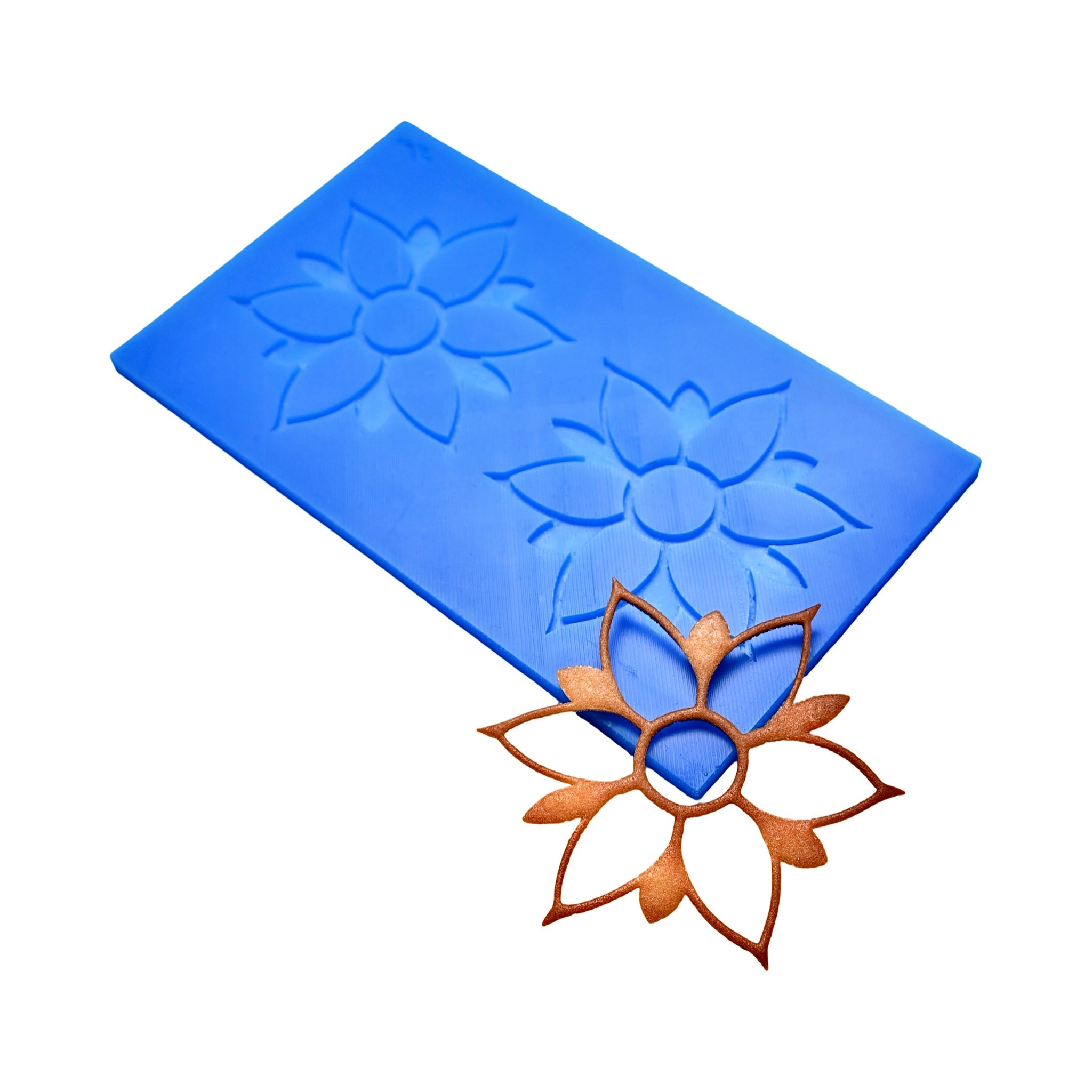 Blue silicone Onalia tuile mat with two flower-shaped molds and a finished bronze tuile.