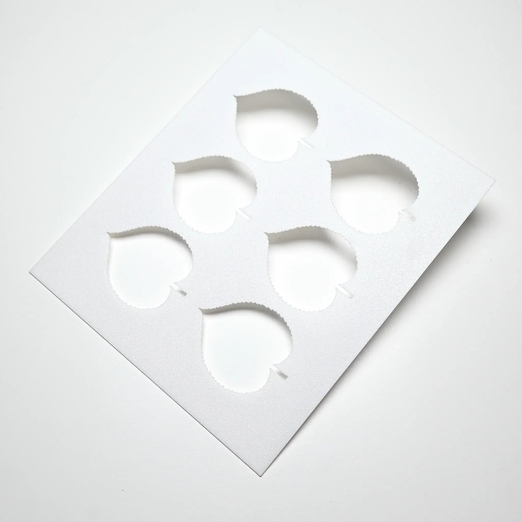 White plastic Linden Leaf stencil featuring six heart-shaped botanical leaf cutouts for pastry design.