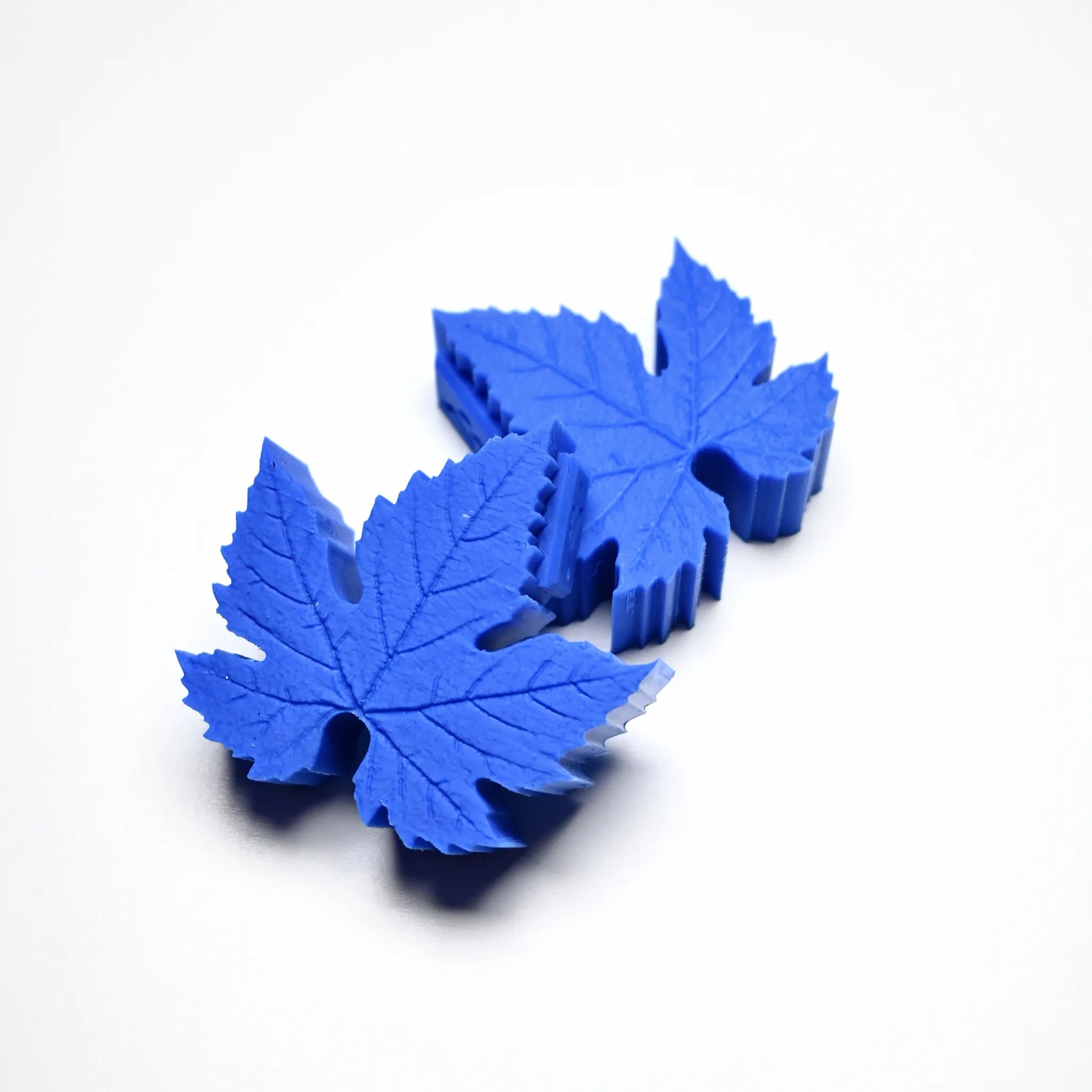 Blue silicone vine leaf molds with detailed vein textures on a white background.