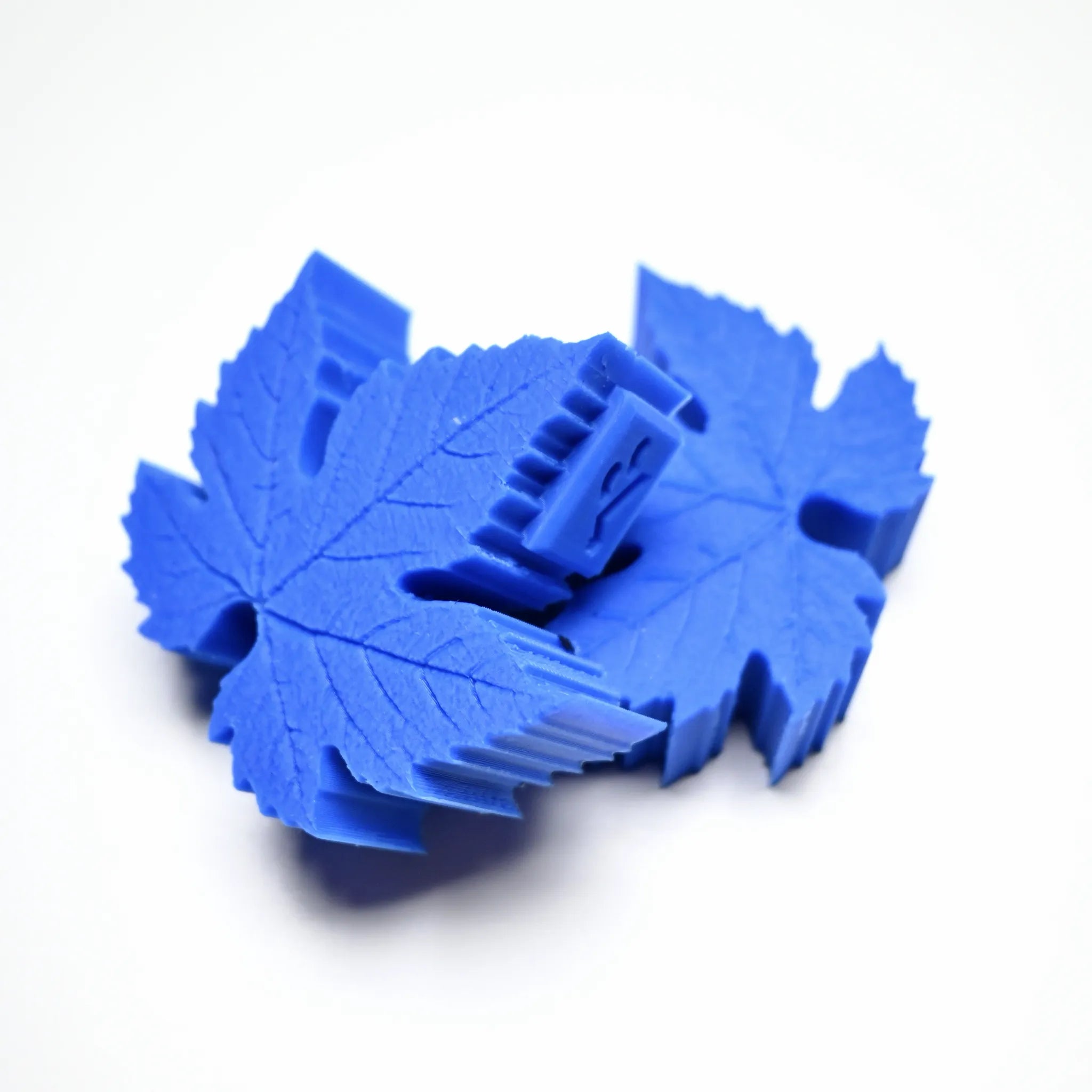 Blue silicone vine leaf press molds with detailed leaf-shaped veining texture.