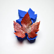 Blue silicone vine leaf mold with a realistic red textured sugar paste leaf on top.