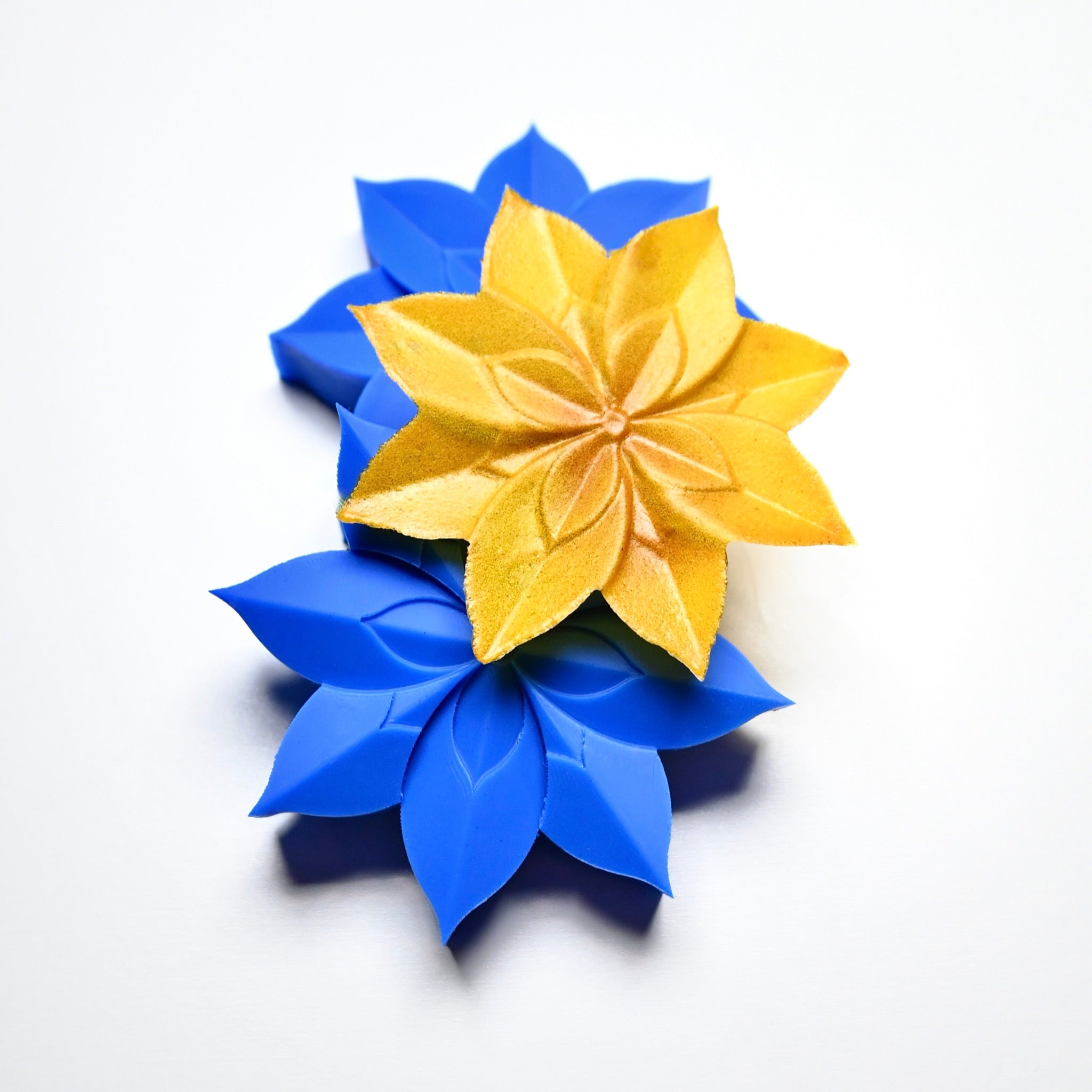 Blue lotus silicone pastry molds with a gold star-shaped lotus tuile on top.