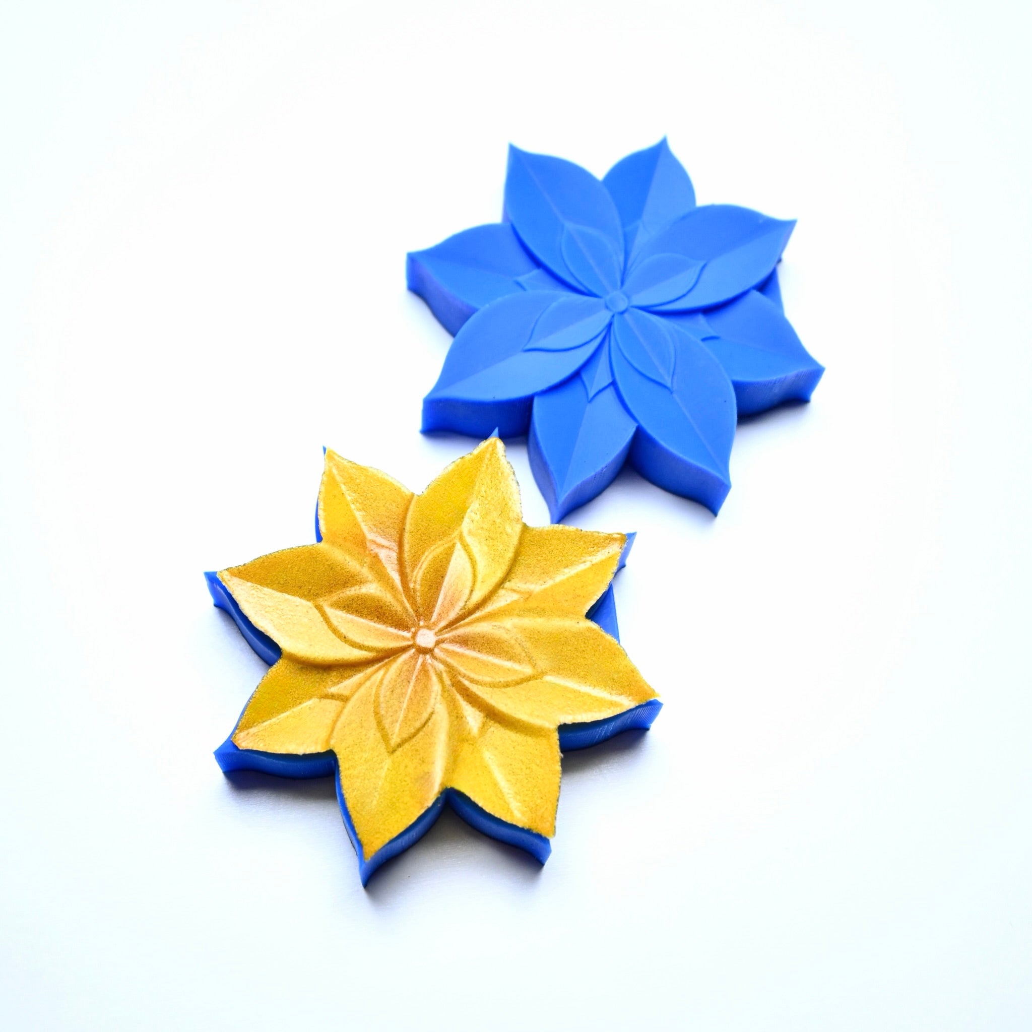 Blue silicone lotus flower mold next to a gold-dusted lotus pastry creation.