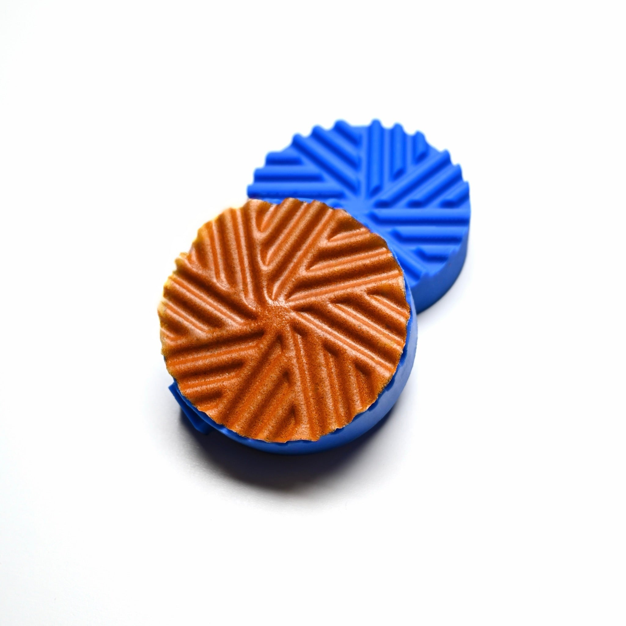 Blue silicone Helix Press molds with a round, spiral-patterned brown pastry.