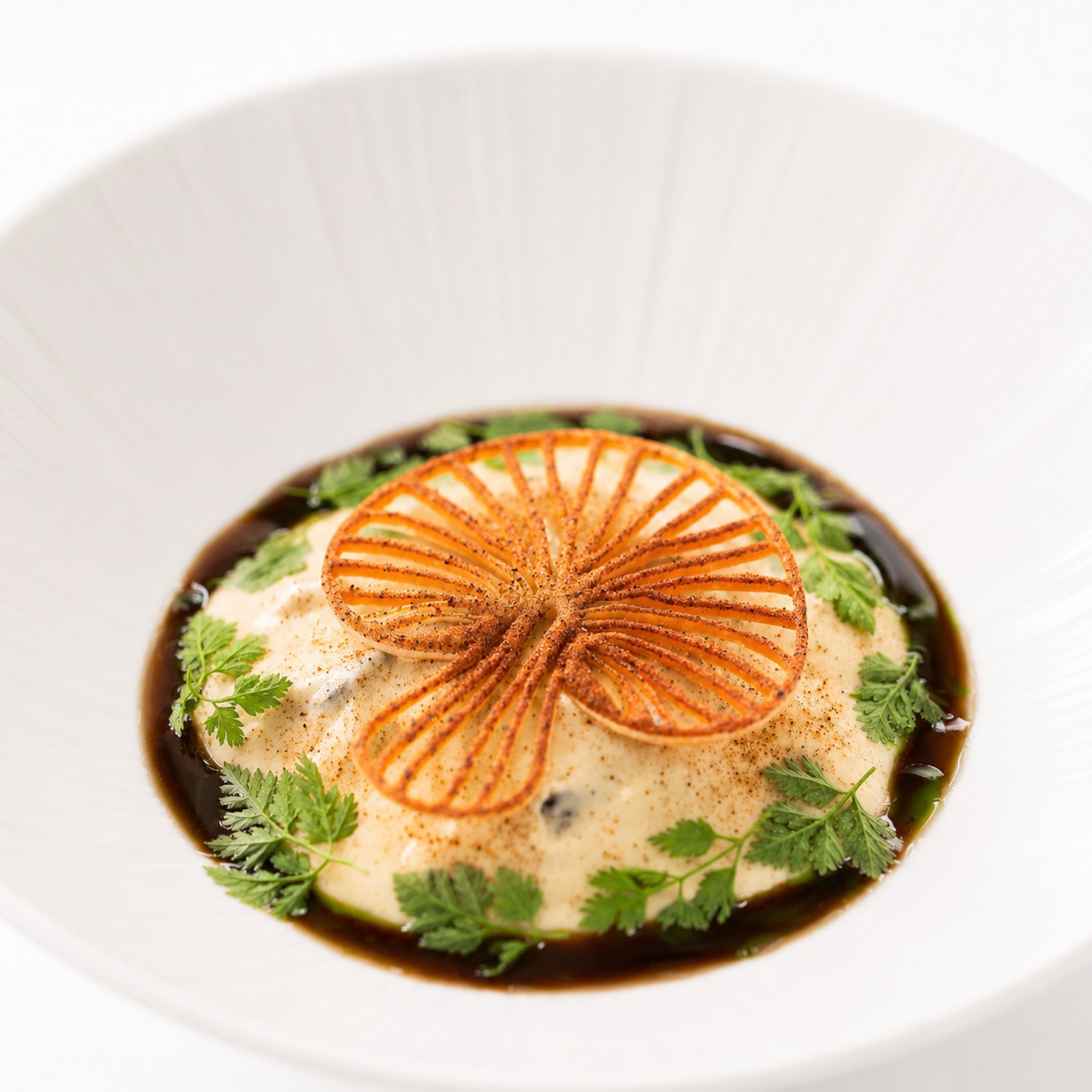 Crispy, golden mushroom-shaped tuile garnish on a gourmet plated dish.