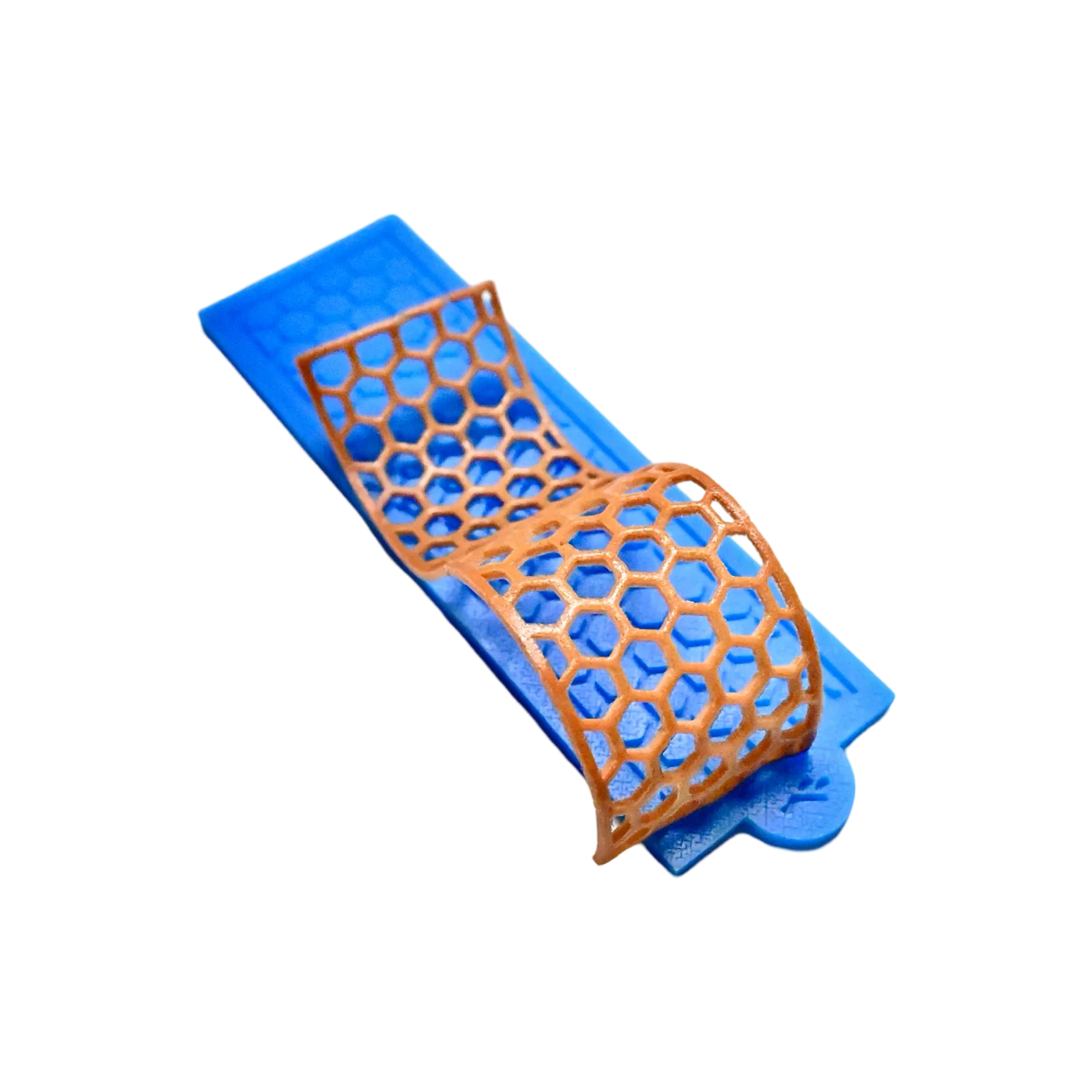 Blue silicone tuile mat with a curved, golden-brown honeycomb-shaped edible decoration.