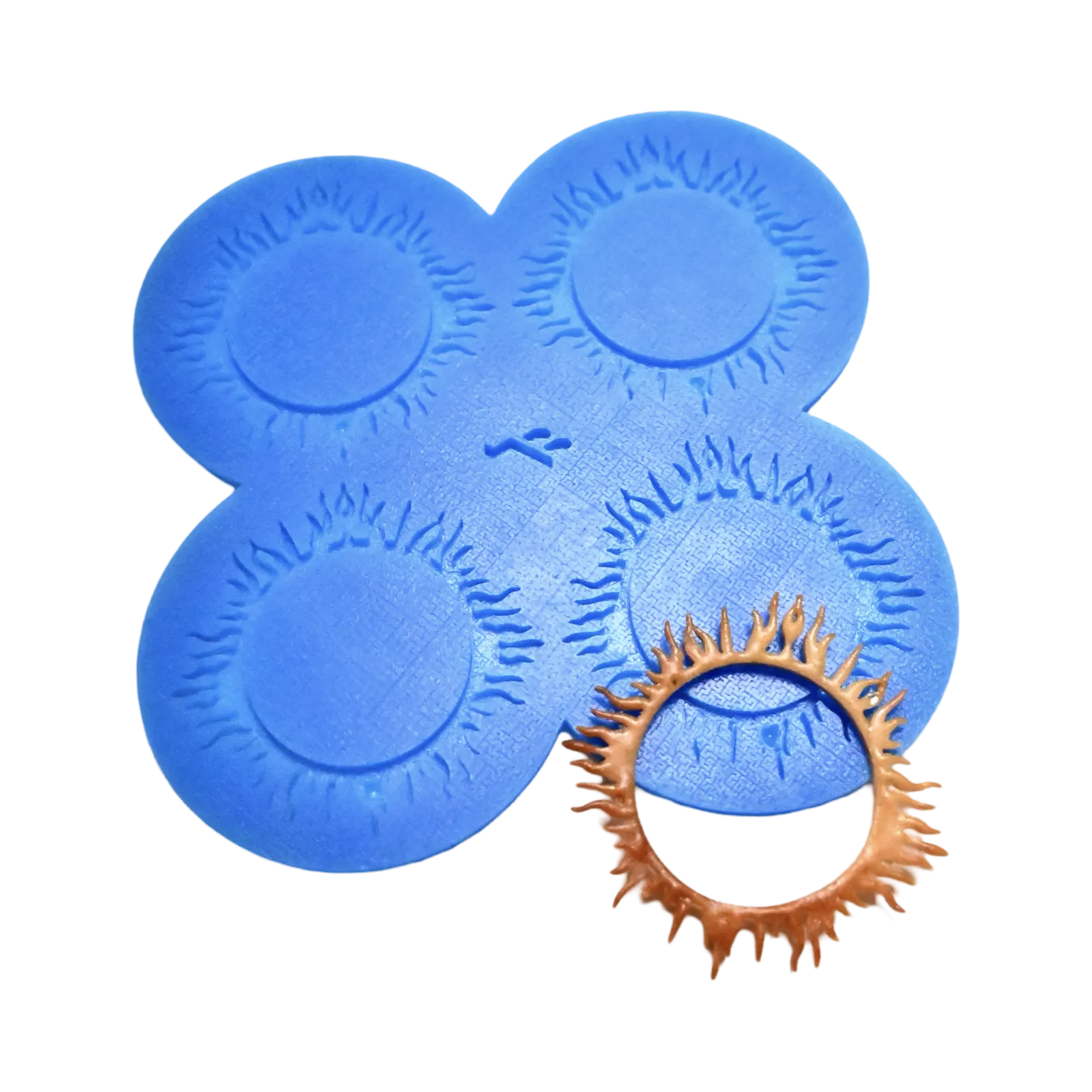 Blue silicone Spirulina tuile mat with four sunburst-shaped molds and a golden-brown baked garnish.