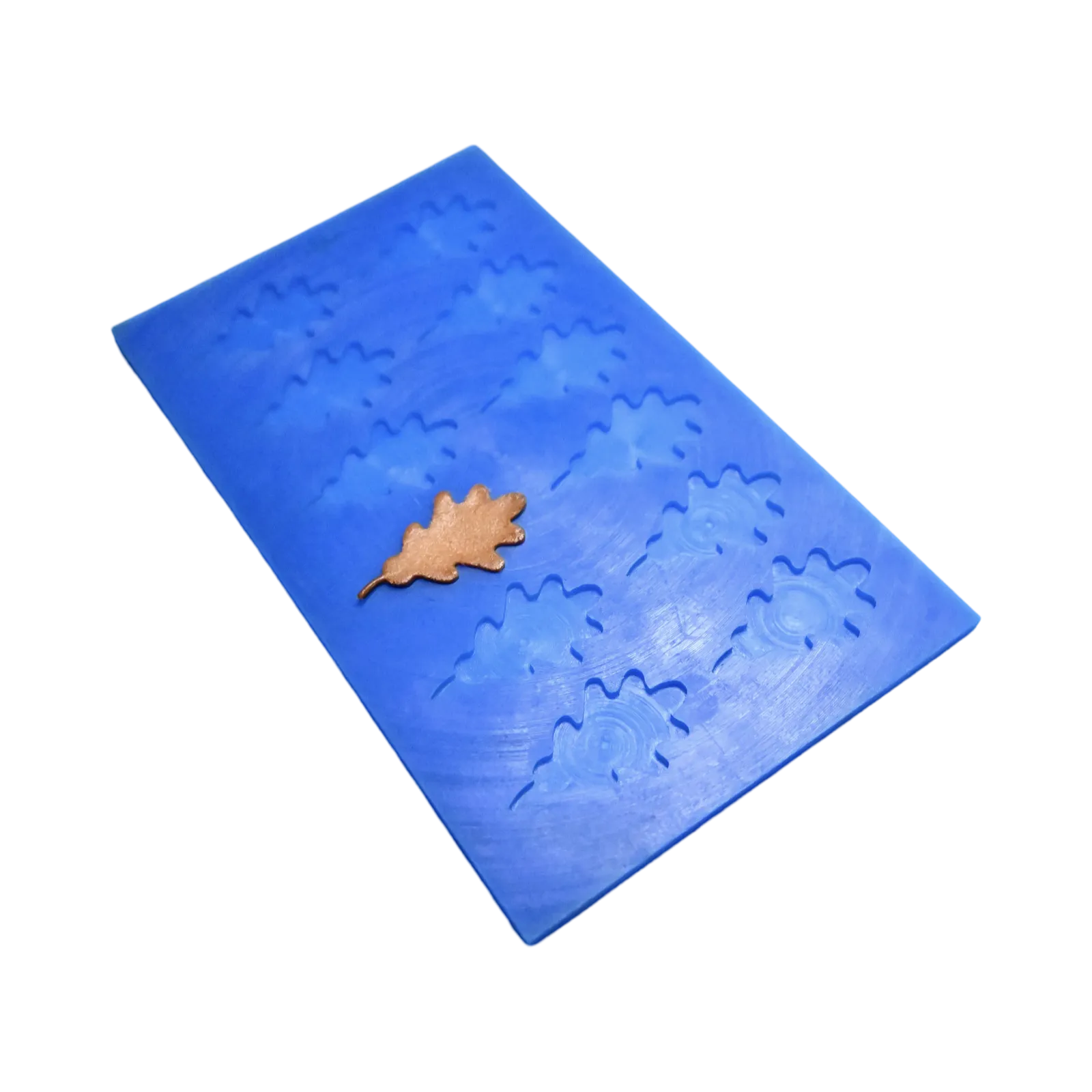 Blue silicone mat with detailed oak leaf shaped molds and a finished brown tuile leaf.