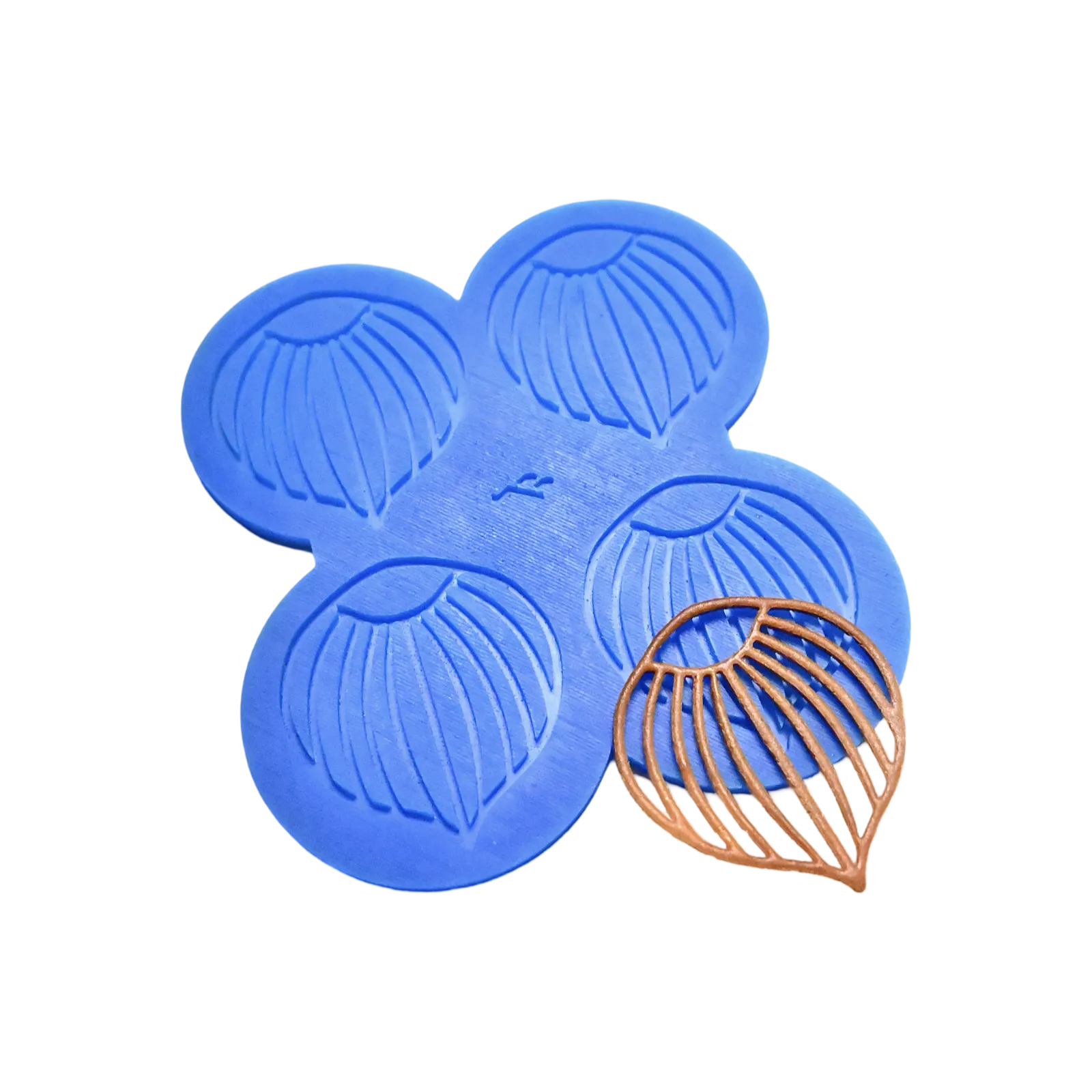 Blue silicone mat with four hazelnut-shaped tuile molds and a finished brown tuile.