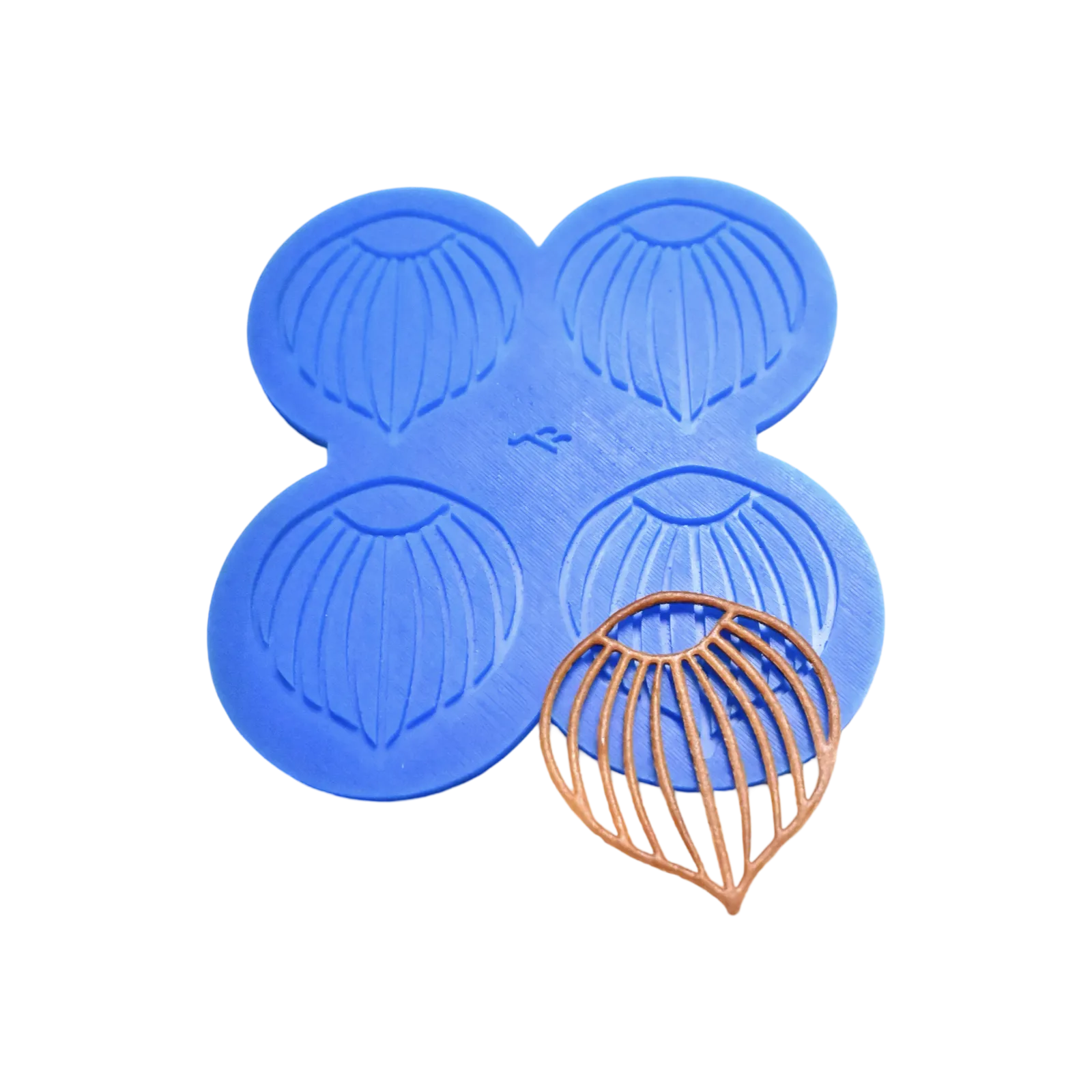 Blue silicone mat with four hazelnut tuile molds and a finished brown tuile.