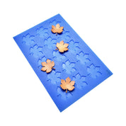 Blue silicone mat with vine leaf shaped molds and golden tuile garnishes.