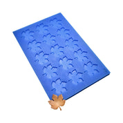 Blue silicone mat with fifteen vine leaf shaped molds and a finished golden tuile leaf.