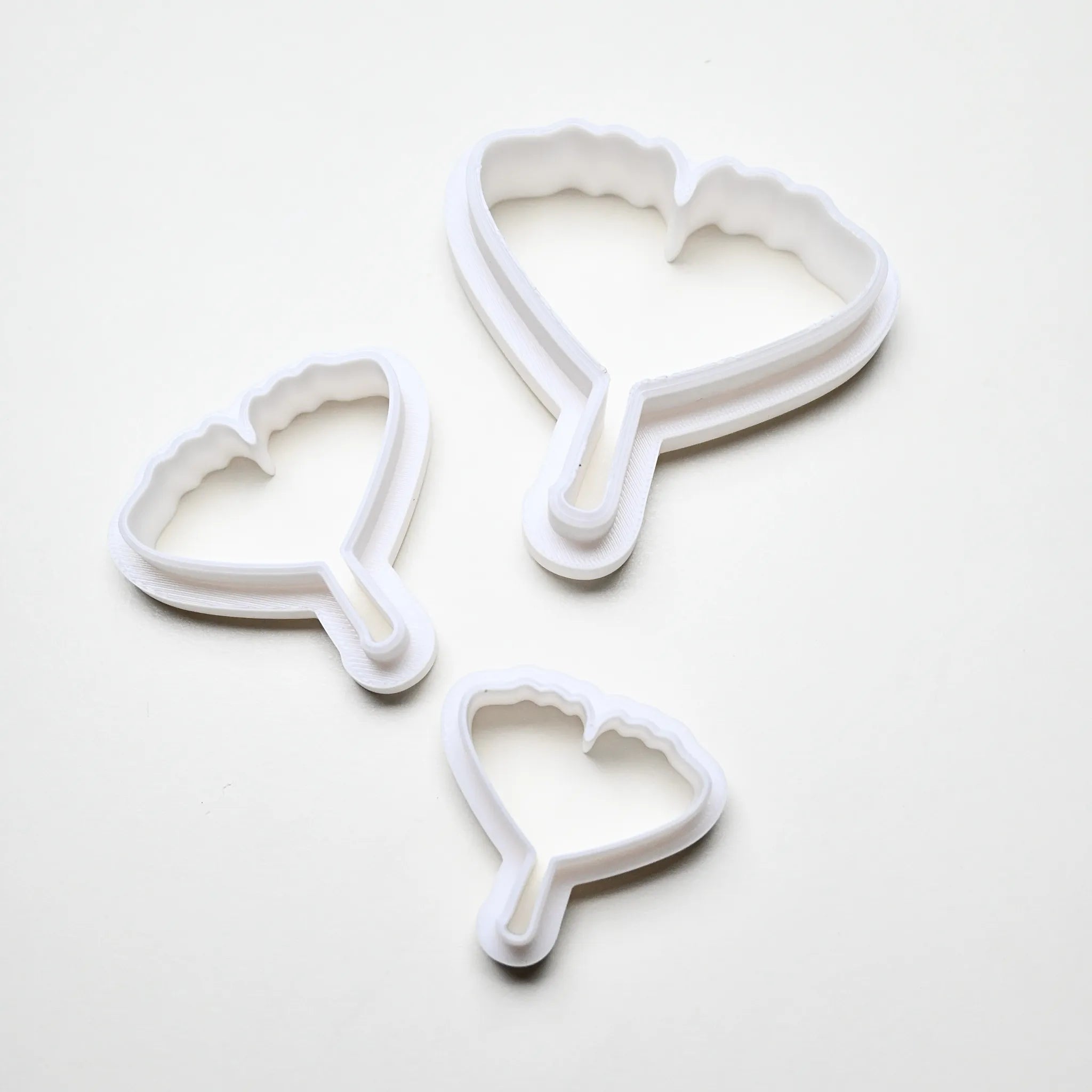 Three white plastic ginkgo leaf cookie cutters in small, medium, and large sizes.