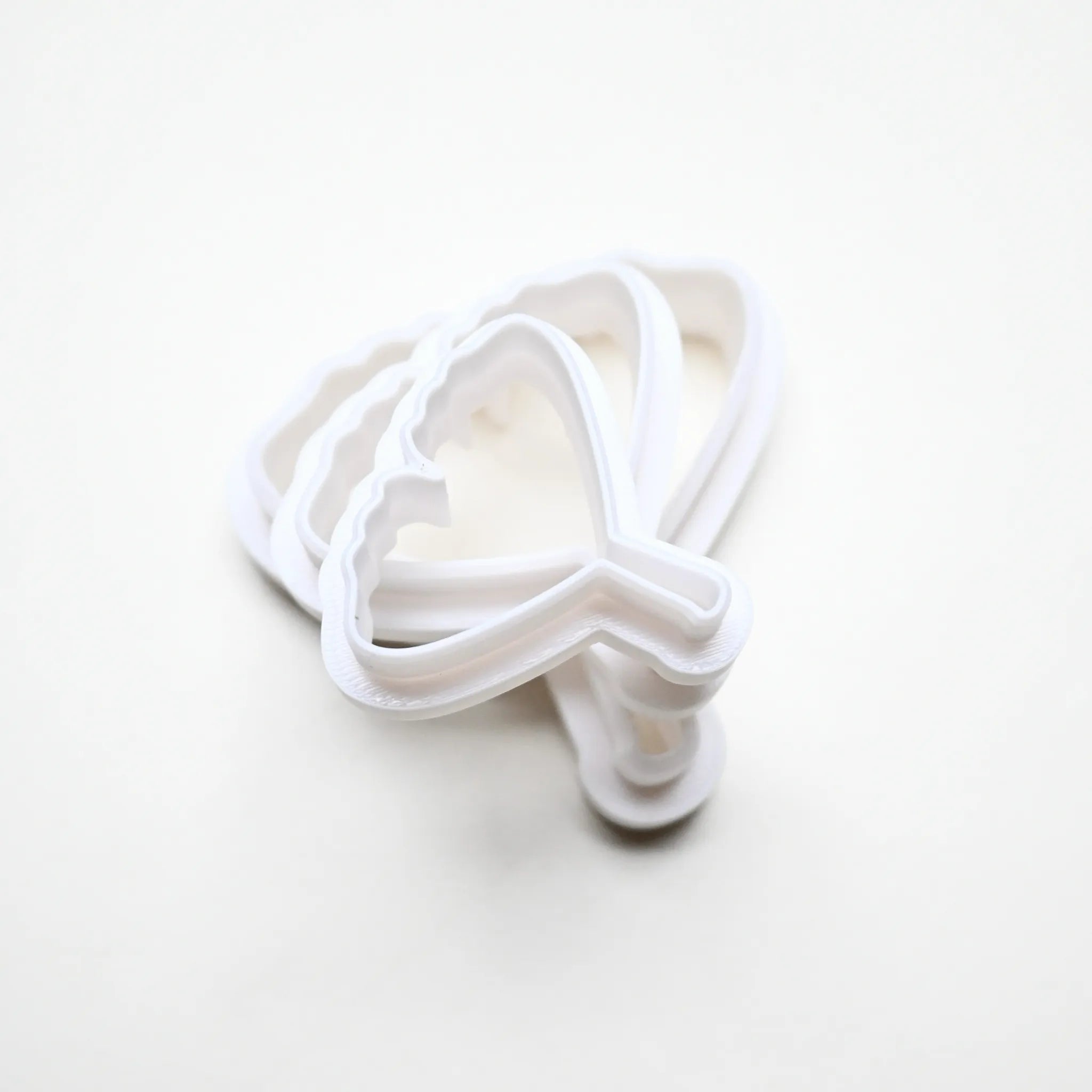 Three white plastic ginkgo leaf cookie cutters in graduated sizes stacked on a white background.