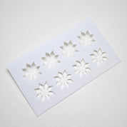 White plastic pastry stencil with eight strawberry calyx star-shaped cutouts.