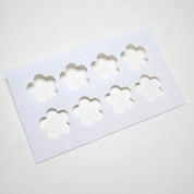 White plastic pastry stencil with eight strawberry flower shaped cutouts.