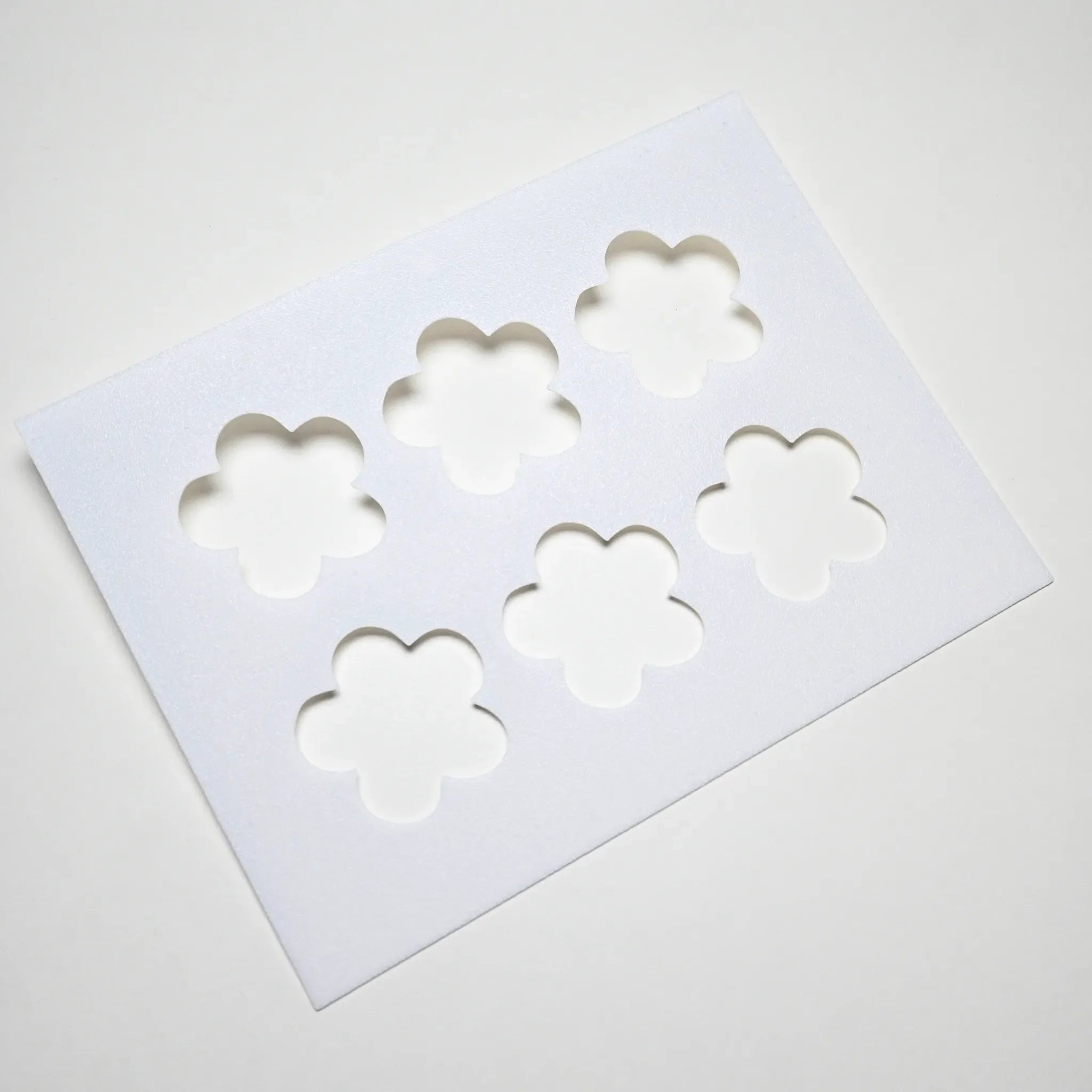 White plastic pastry stencil with six five-petal strawberry flower cutouts.