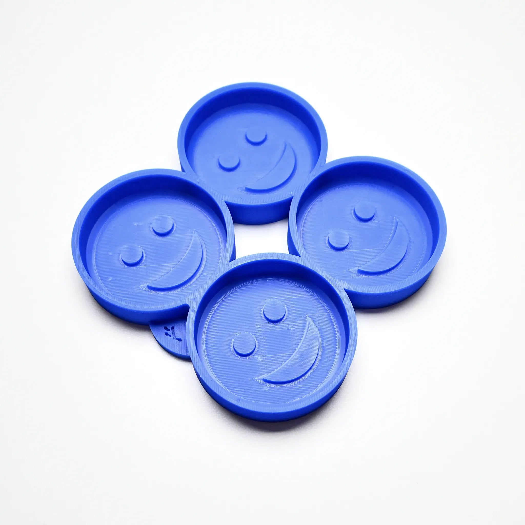 Blue silicone mold with four round smiley face cavities for pastry and chocolate.