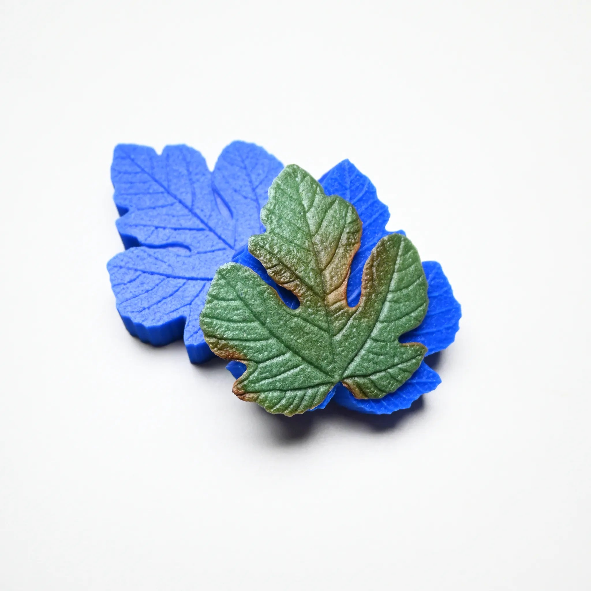 Blue silicone fig leaf veiner mold with a realistic green fondant leaf on top.