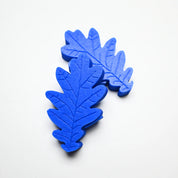 Two blue silicone oak leaf pastry molds with detailed vein textures on a white background.