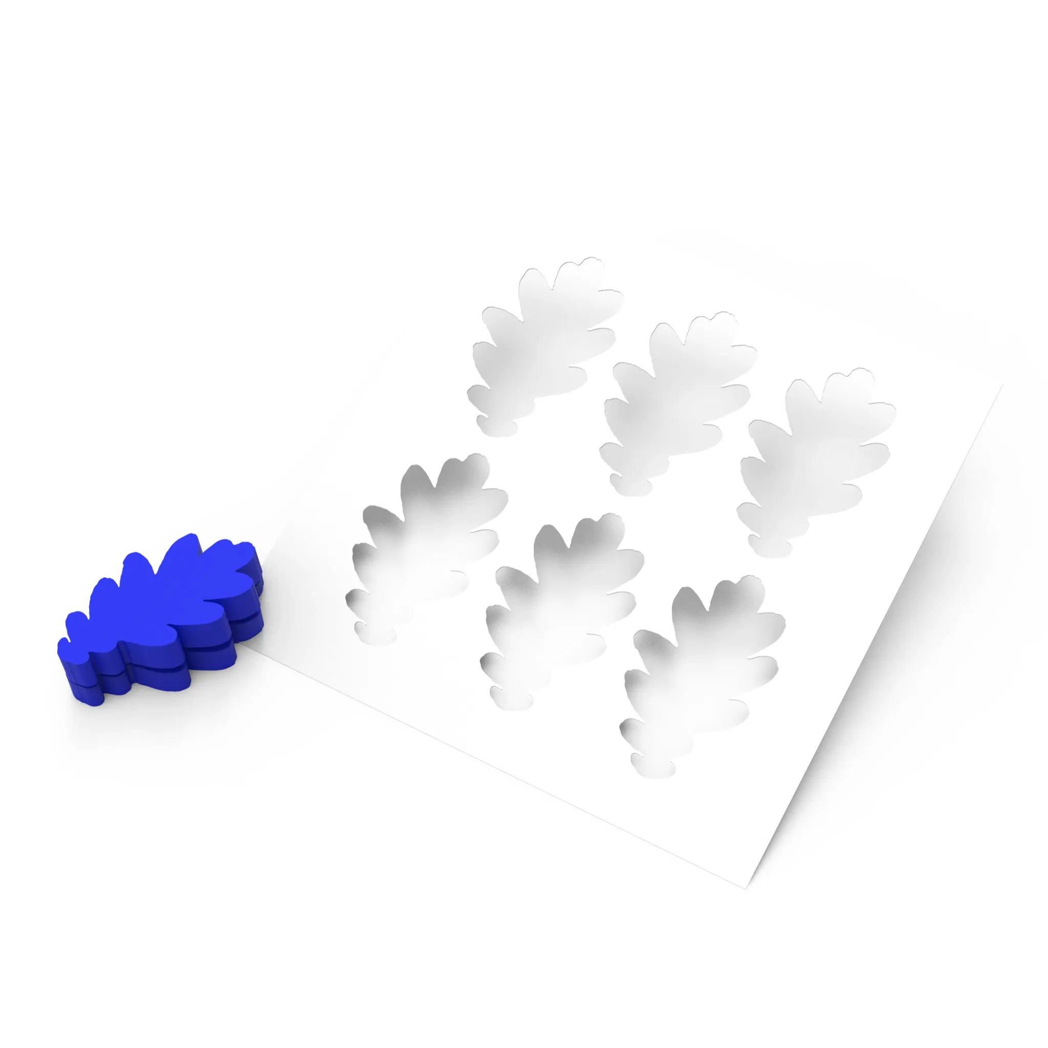 White silicone pastry mold with six oak leaf-shaped cavities next to a blue oak leaf press tool.