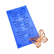 Blue silicone Papirys tuile mat with butterfly-shaped molds and a finished bronze tuile.