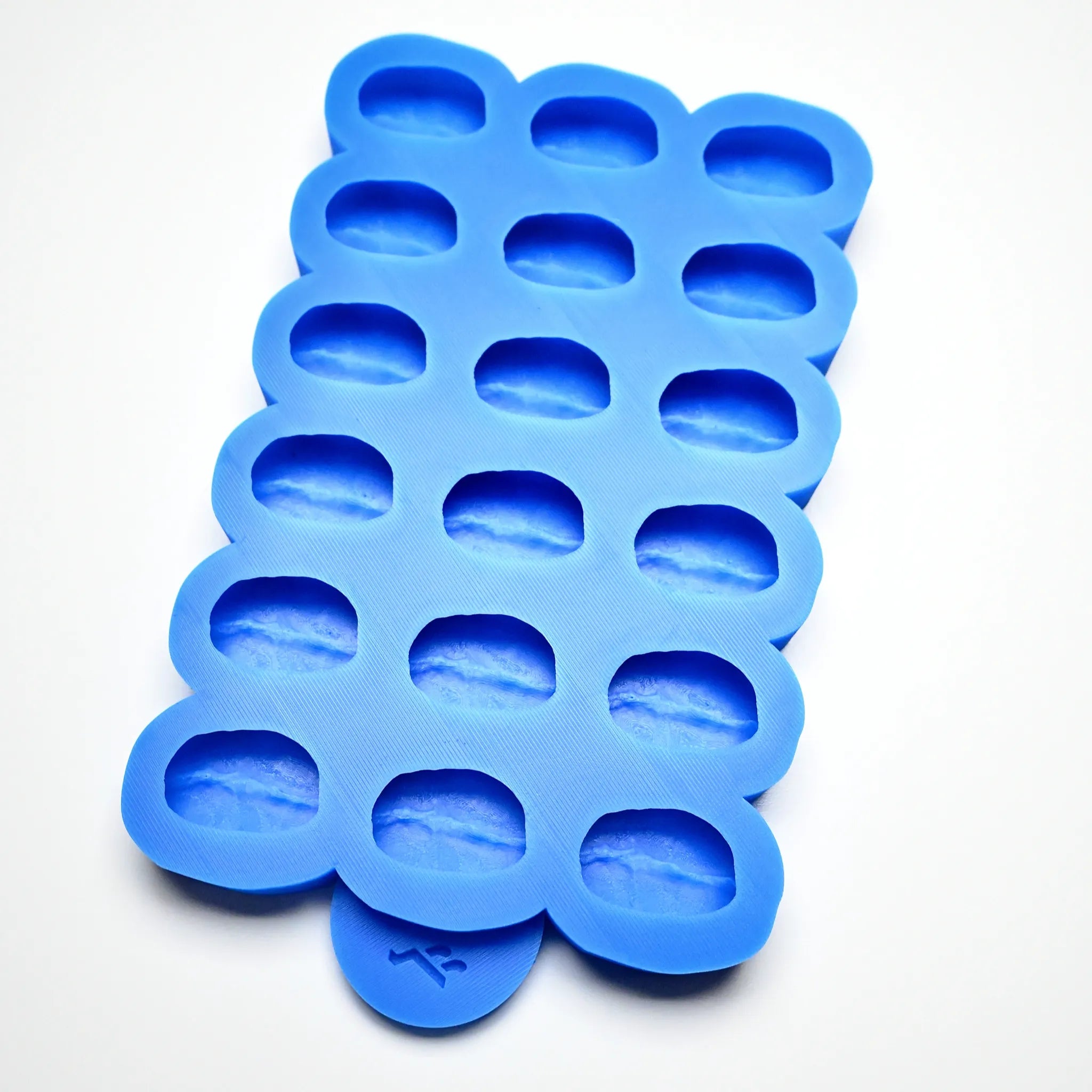 Blue silicone mold with eighteen coffee bean shaped cavities.