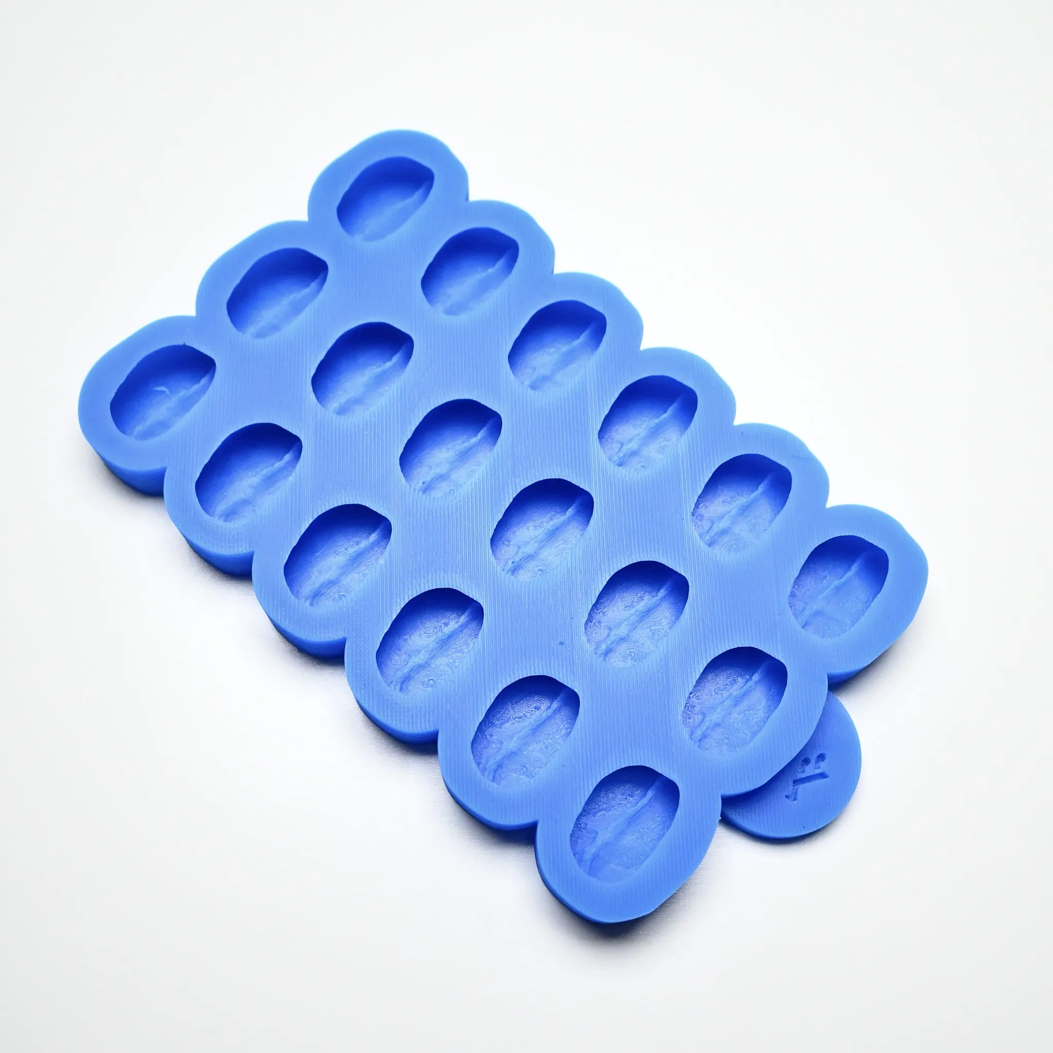 Blue silicone mold with multiple coffee bean-shaped cavities on a white background.