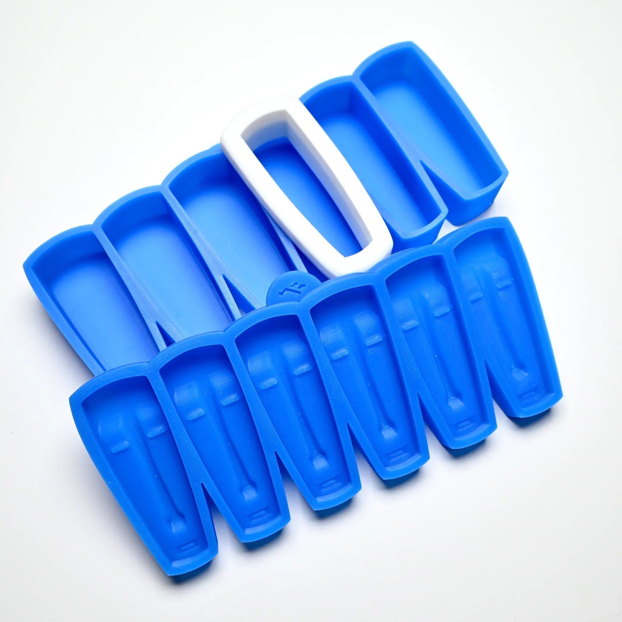 Blue silicone pastry mold with elongated, mask-shaped cavities and a white plastic cutter.