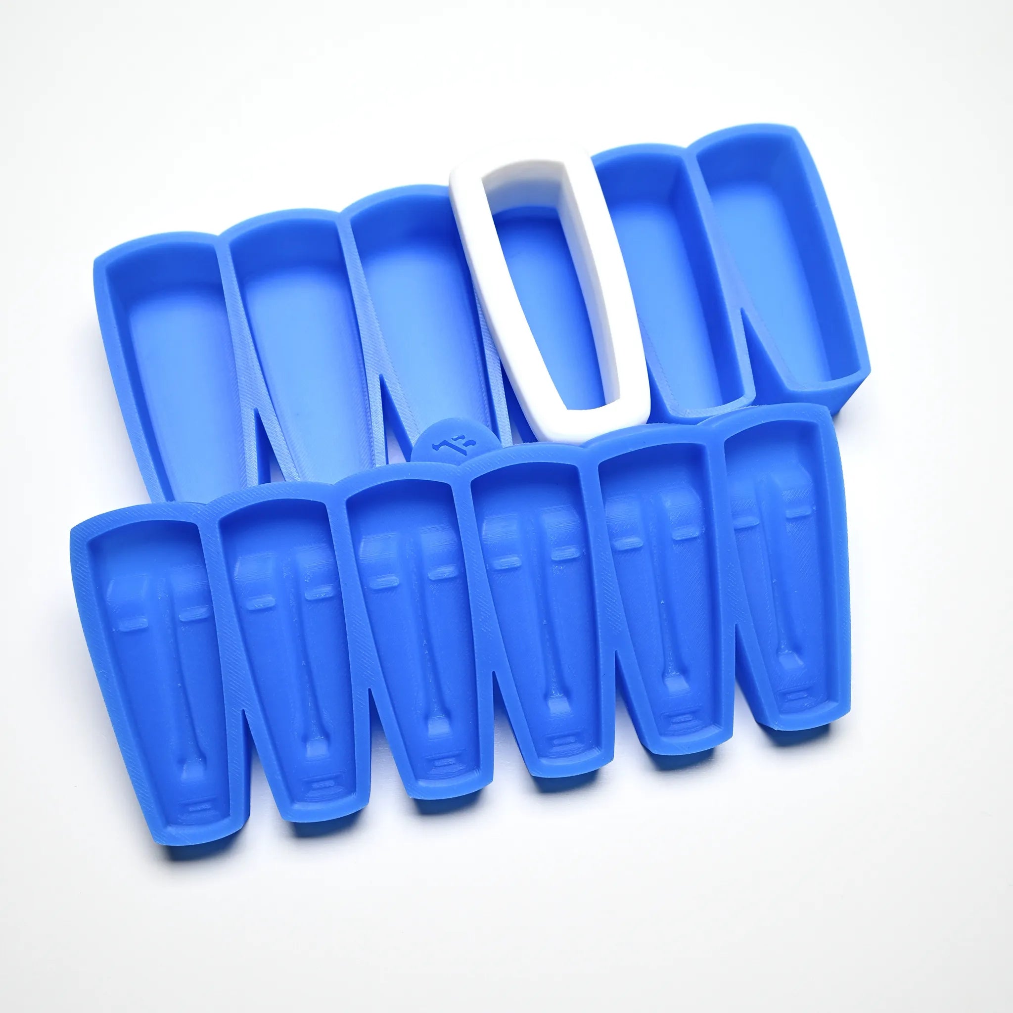Blue silicone pastry molds with elongated, stylized mask shapes and a white plastic cutter.