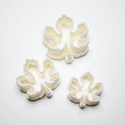 Three white plastic fig leaf cookie cutters in small, medium, and large sizes.