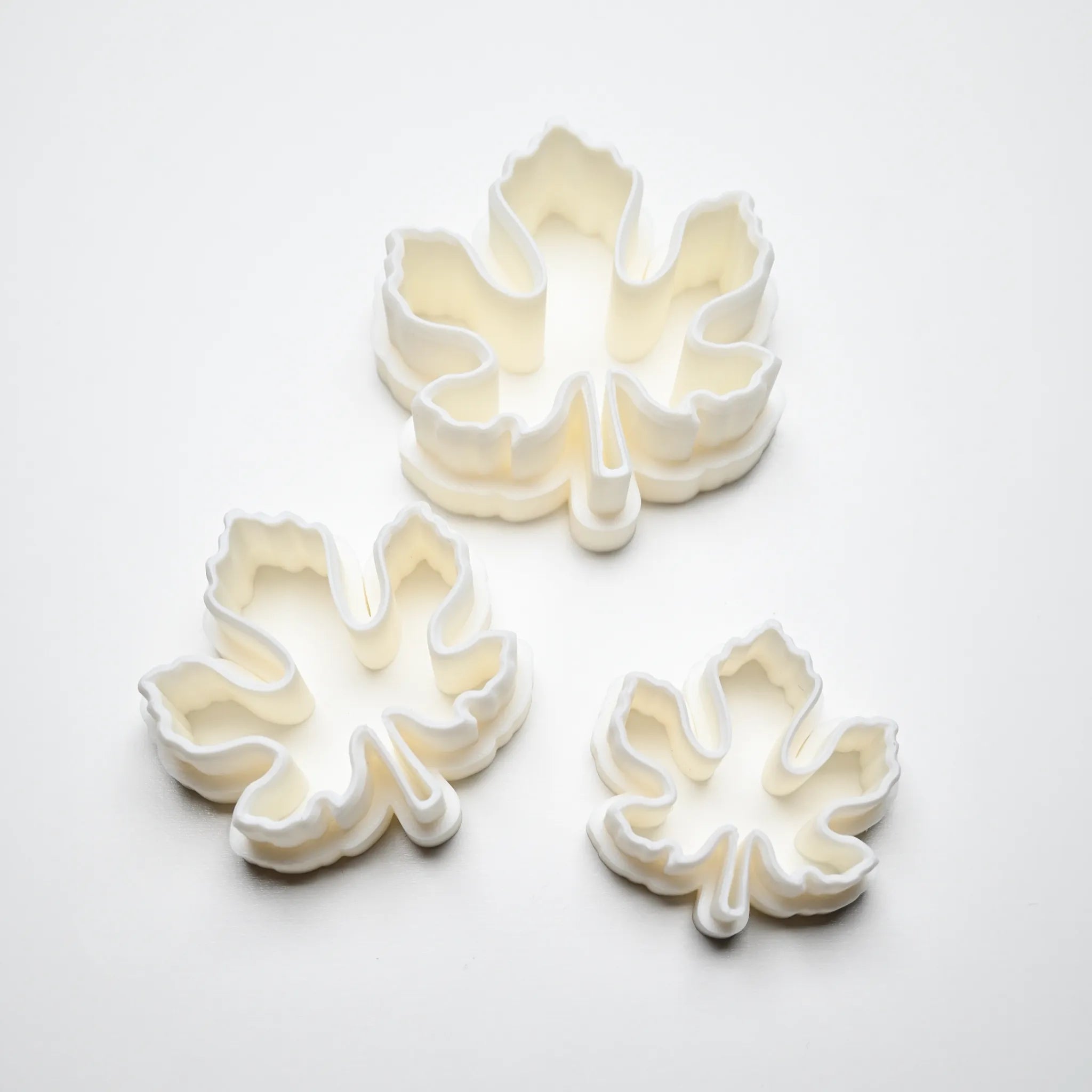 Three white plastic fig leaf cookie cutters in small, medium, and large sizes.